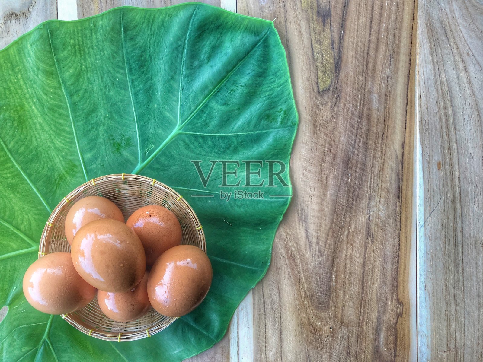 稻草篮子里的新鲜鸡蛋，背景是绿色的树叶照片摄影图片