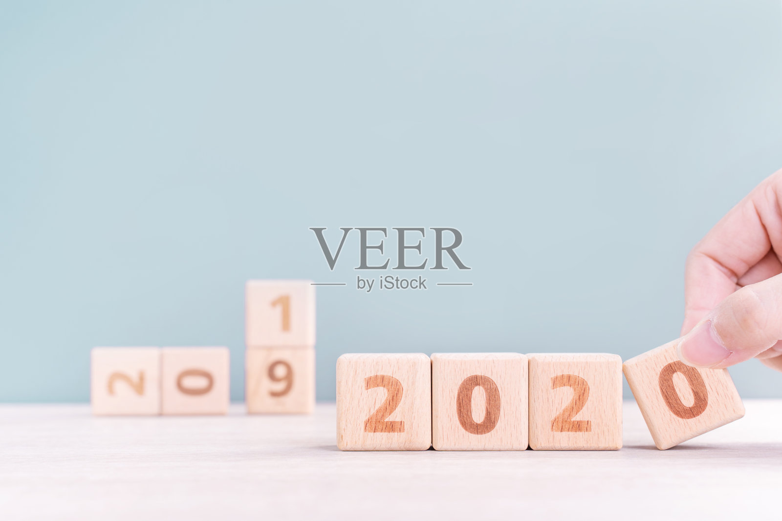 2020年& 2019年新年倒计时设计理念——女子手持木桌、绿色背景的木块立方体。照片摄影图片