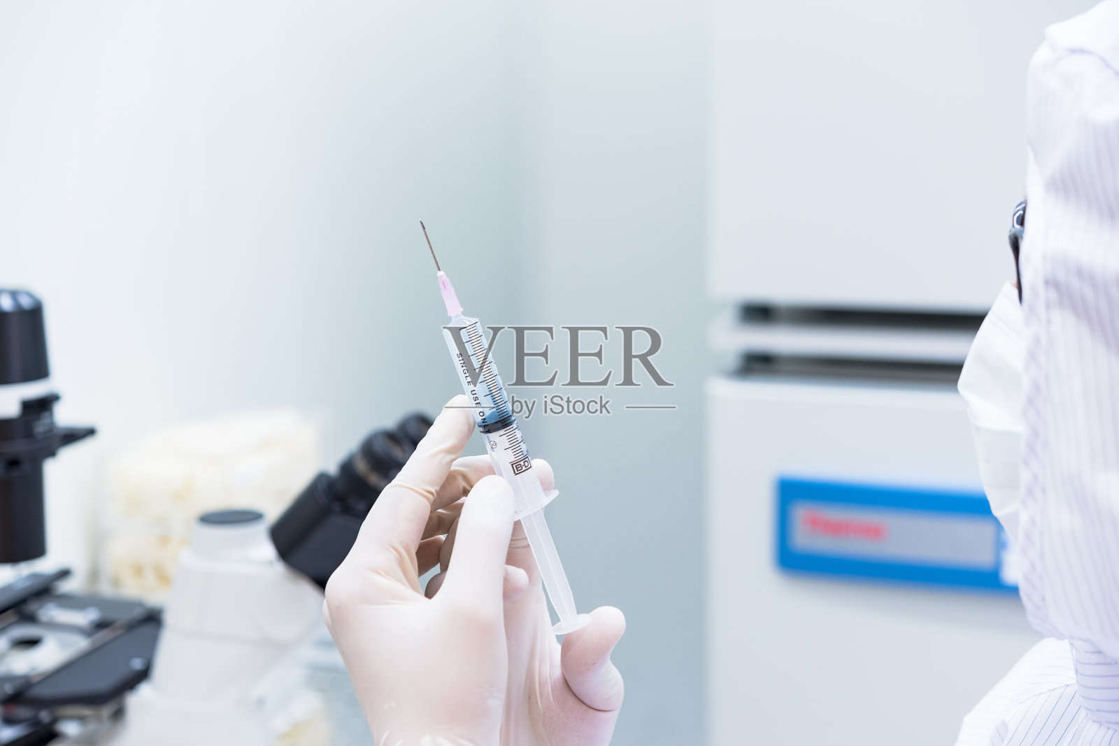穿着无菌工作服拿着注射器进行医学研究的科学家照片摄影图片