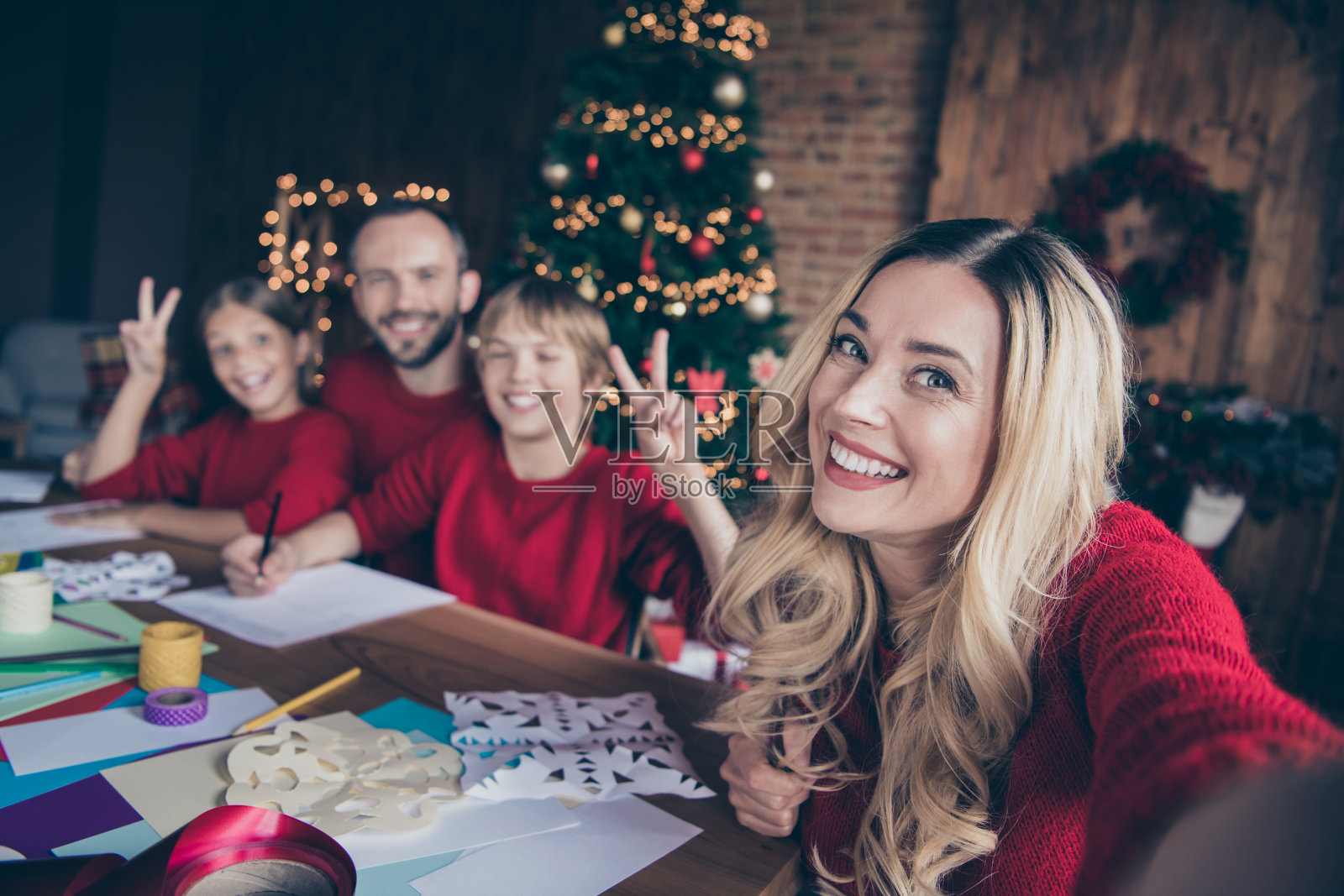 大家族的照片，爸爸妈妈和两个孩子一起度过圣诞夜写圣诞老人祝福信拍摄自拍坐在桌子室内穿红色毛衣照片摄影图片