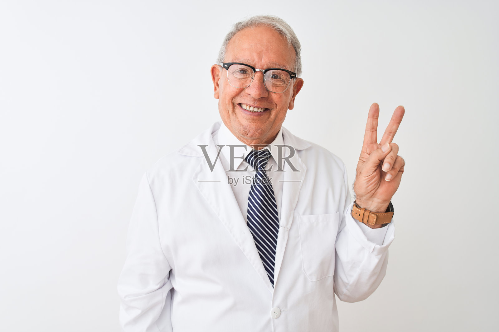 白发苍苍的资深科学家身穿大衣站在孤立的白色背景微笑着，快乐的脸对着镜头眨着眼睛做胜利手势。二号人物。照片摄影图片
