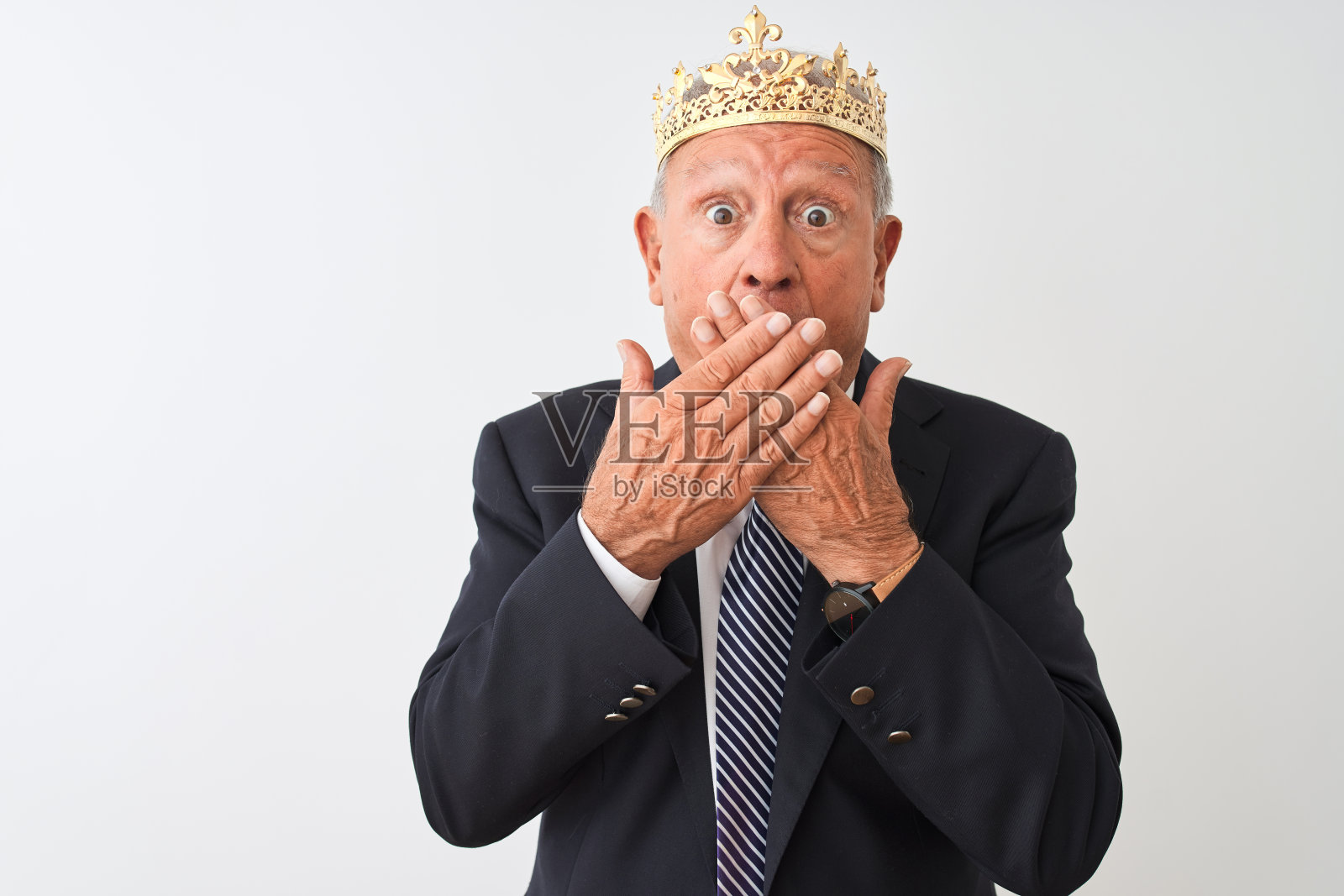 白发苍苍的资深商人戴着皇冠越过孤立的白色背景震惊地用手捂住了嘴。秘密的概念。照片摄影图片
