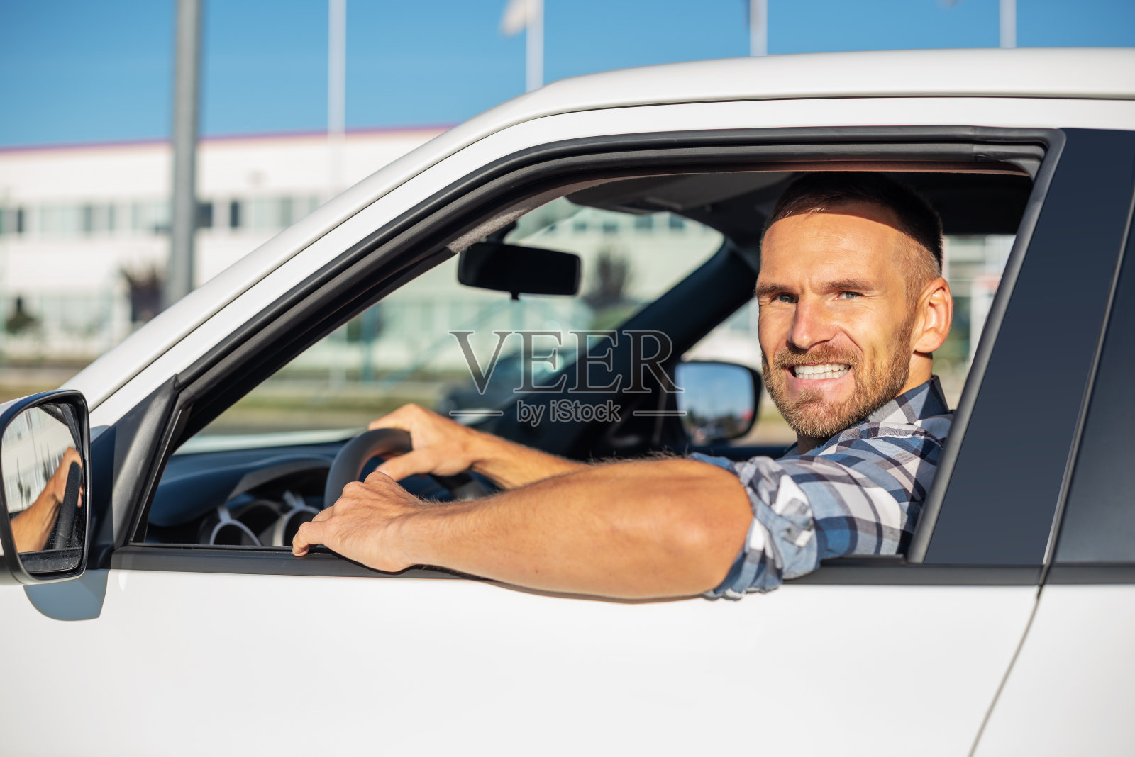 帅气的男人开着一辆白色的车。照片摄影图片