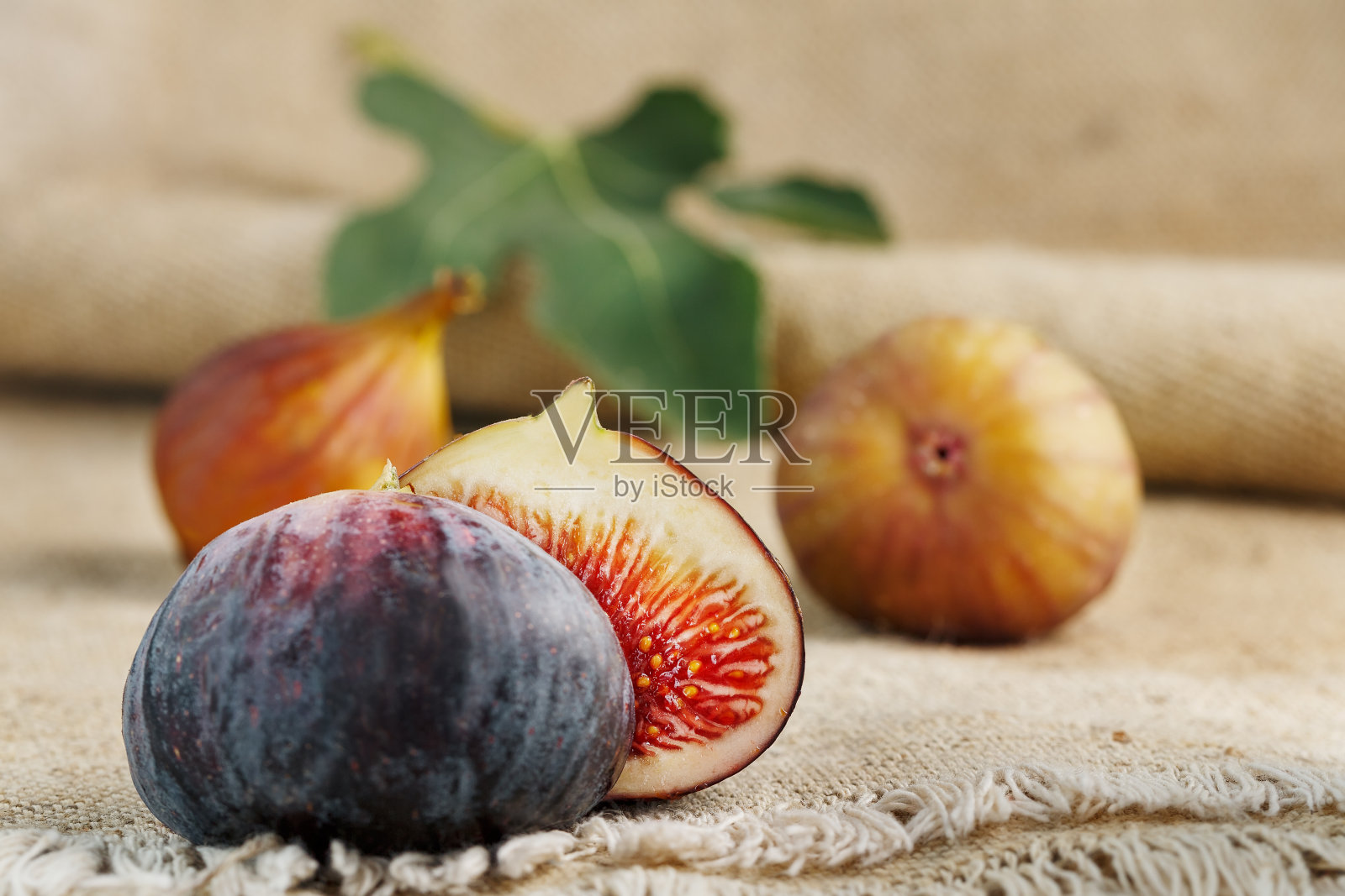 桌子上有无花果，一组水果放在一个用粗麻布做的木制农场桌子上。带果肉的无花果片。健康美味的水果照片摄影图片