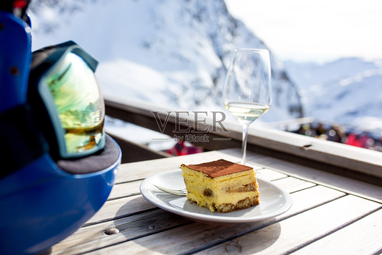 头盔里是雪山的倒影，桌上是一杯葡萄酒和一盘提拉米苏，蒂罗尔照片摄影图片