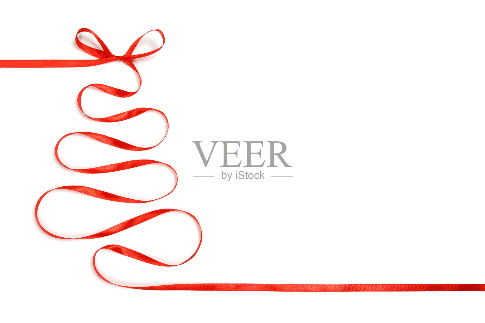 白色背景上有一个用红丝带做成的蝴蝶结的圣诞树。照片摄影图片