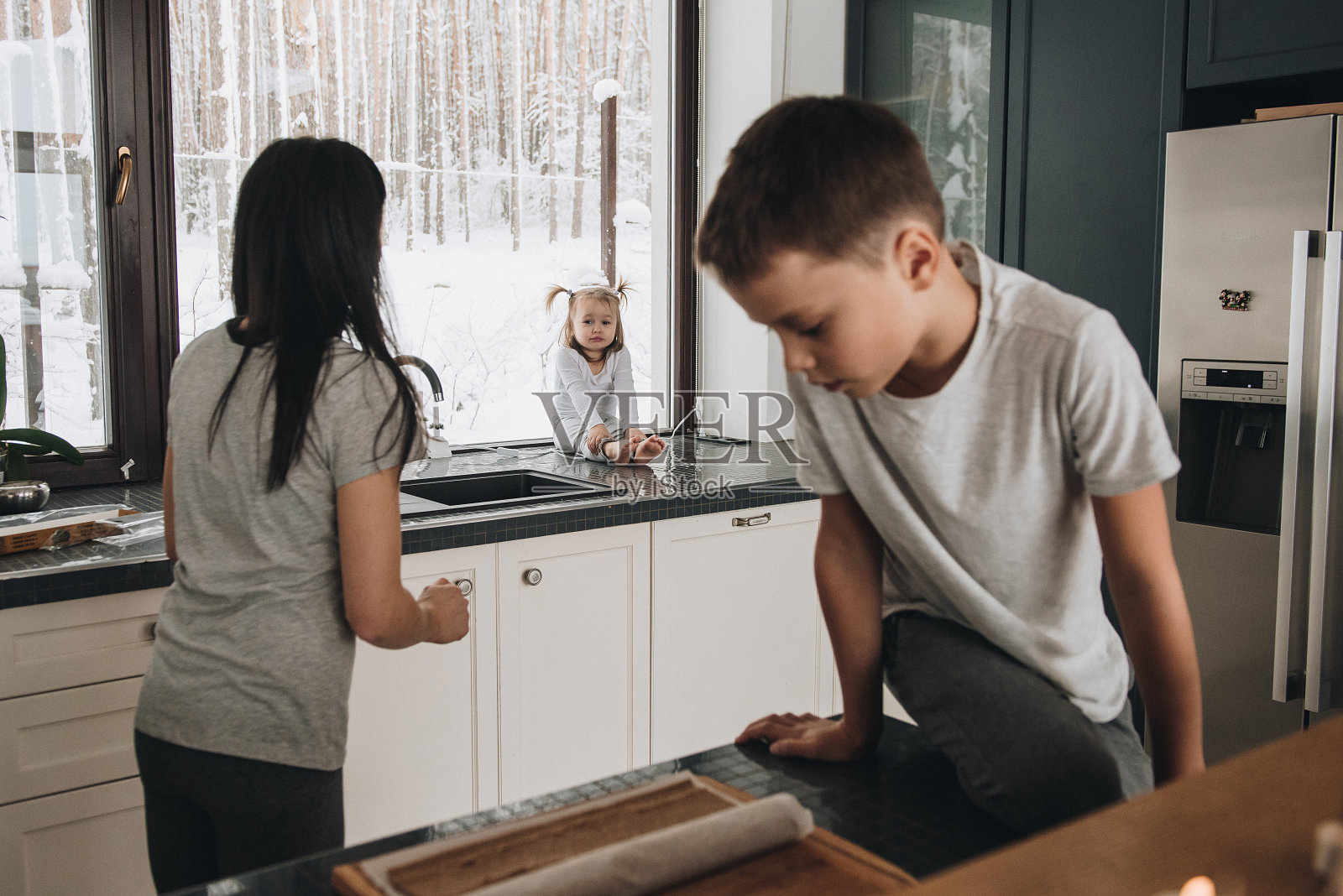 一家人坐在窗前，看着冬天的森林。新年好精神。早上穿着睡衣照片摄影图片