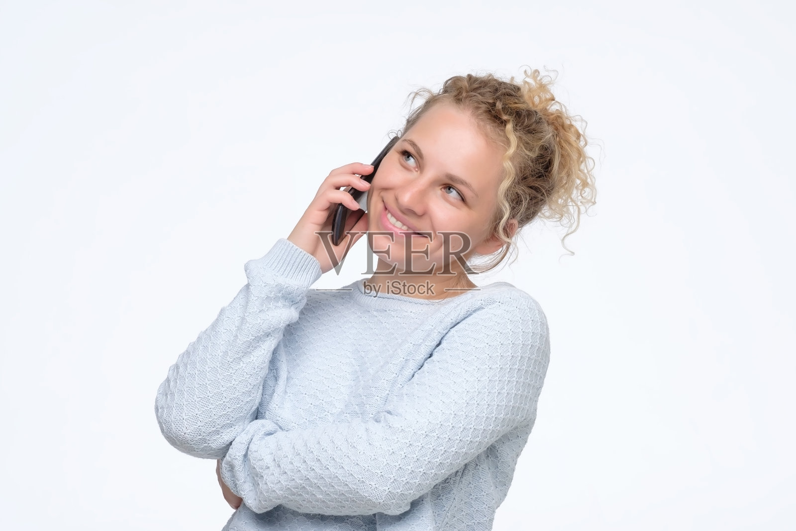 一个穿着蓝色毛衣的女人正在和她的男朋友通电话。照片摄影图片