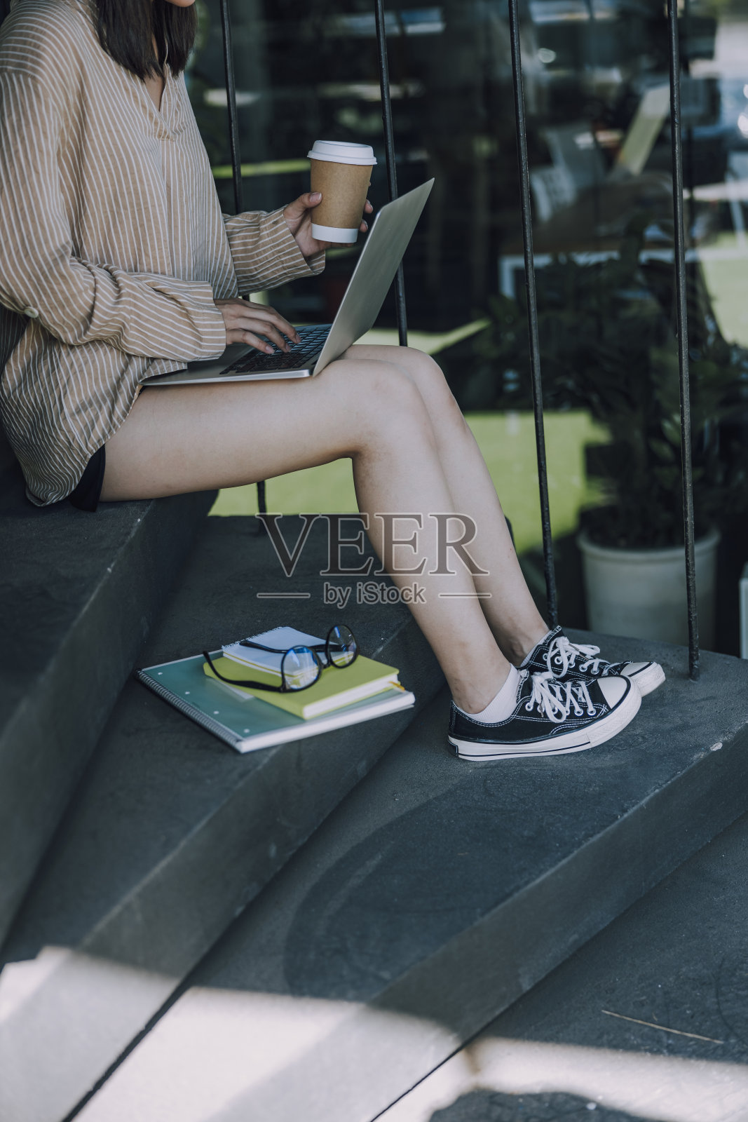 拿着杯托坐在楼梯上的年轻女士照片摄影图片