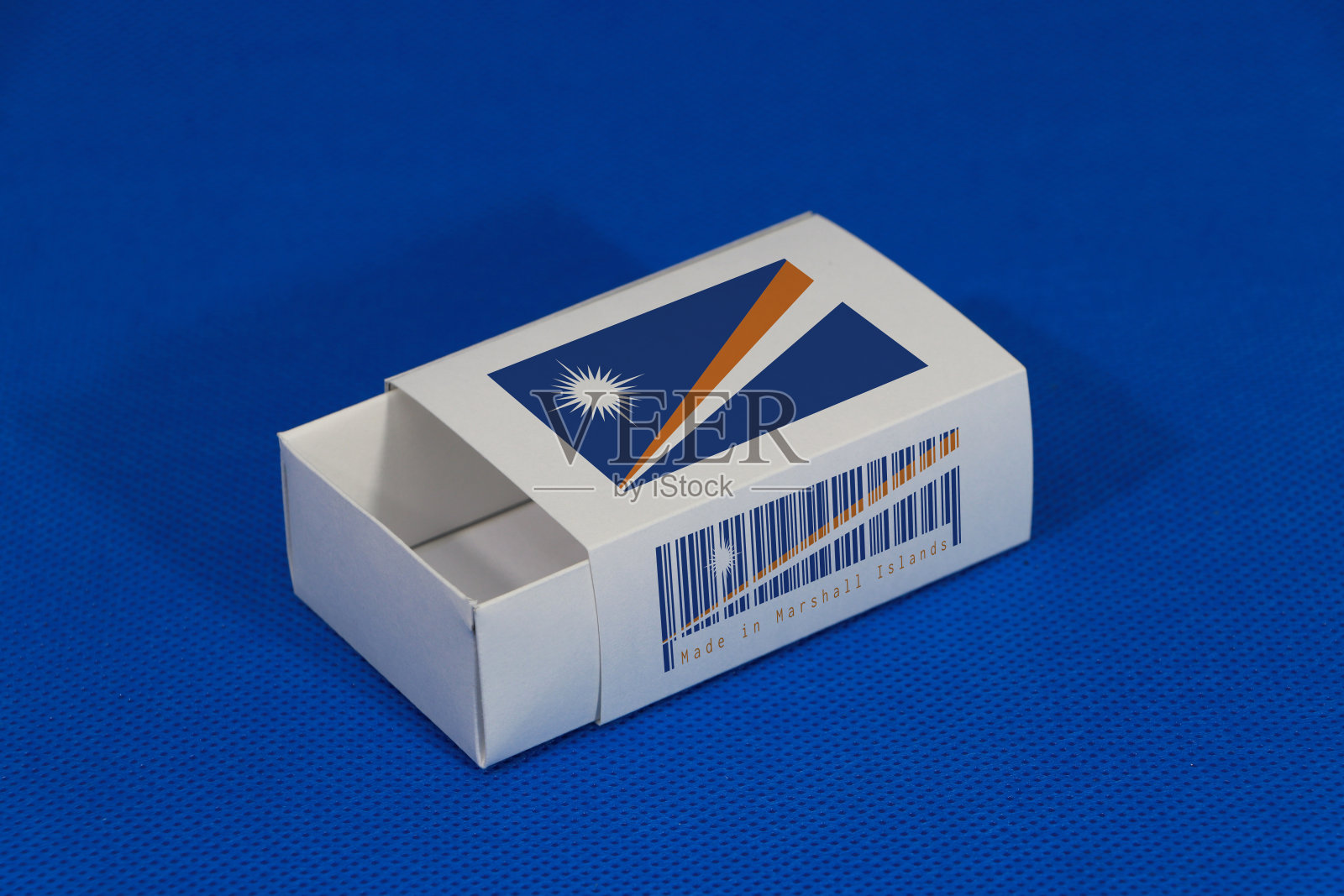 马歇尔国旗上的白色包装盒配上条码和国旗颜色上的蓝色背景，纸包装上放火柴或产品。照片摄影图片