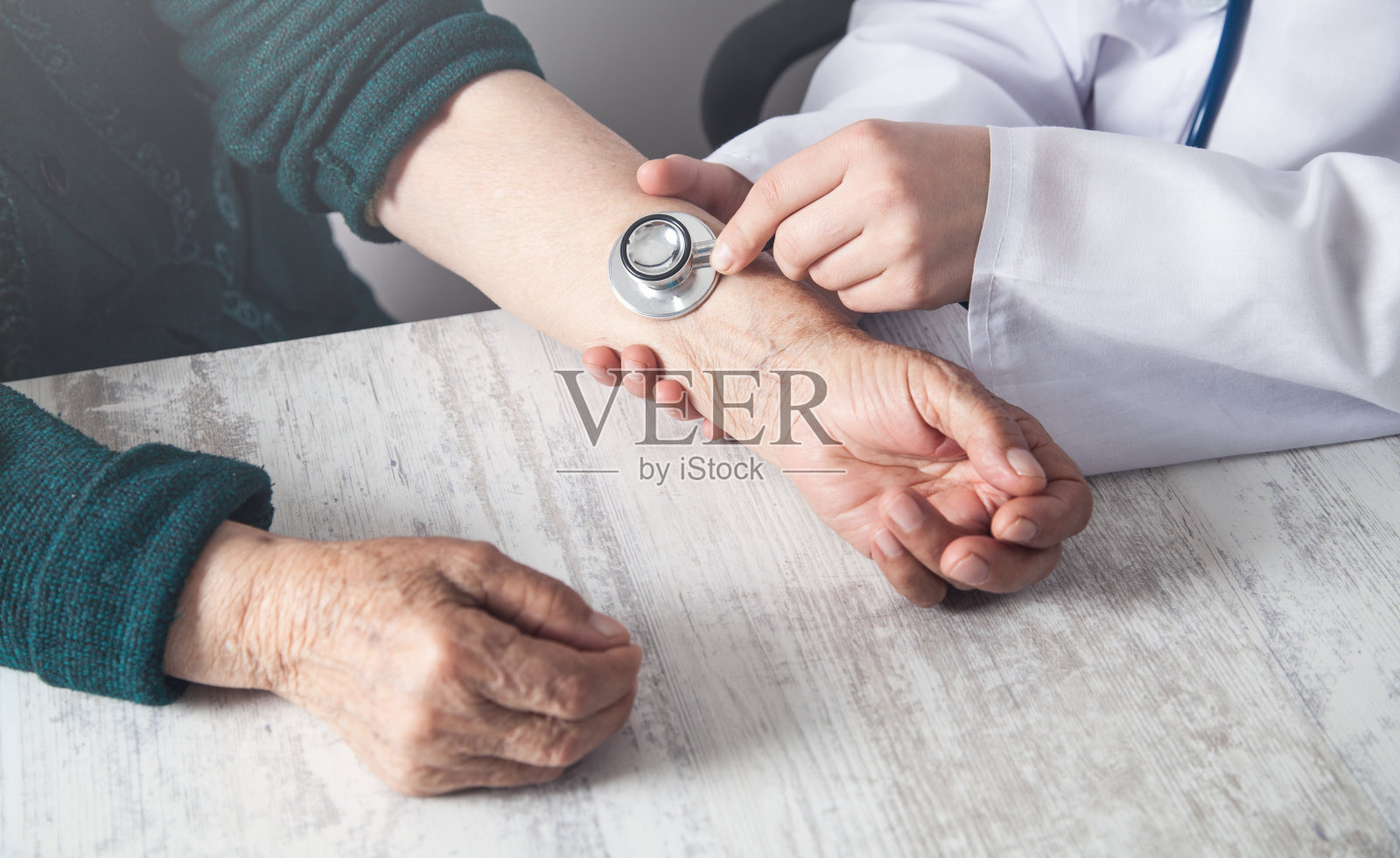 医生用听诊器检查老年妇女。照片摄影图片