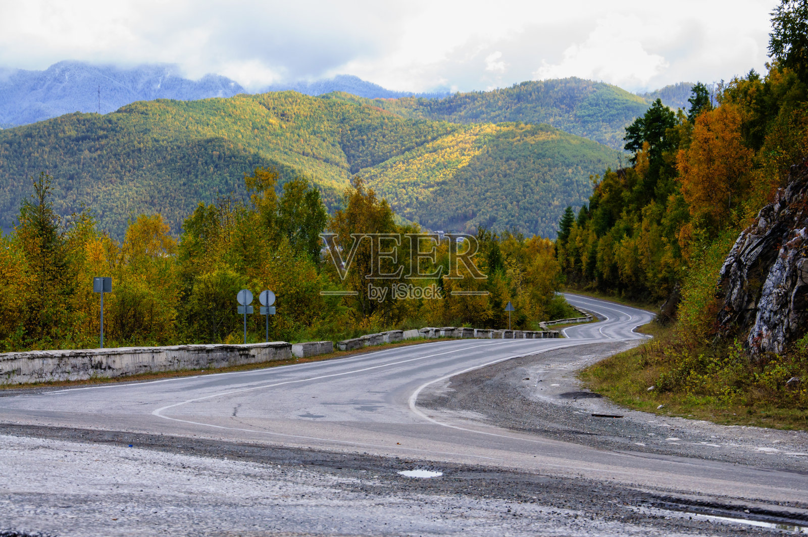 一条弯弯曲曲的秋路，远处有五颜六色的森林和高山照片摄影图片