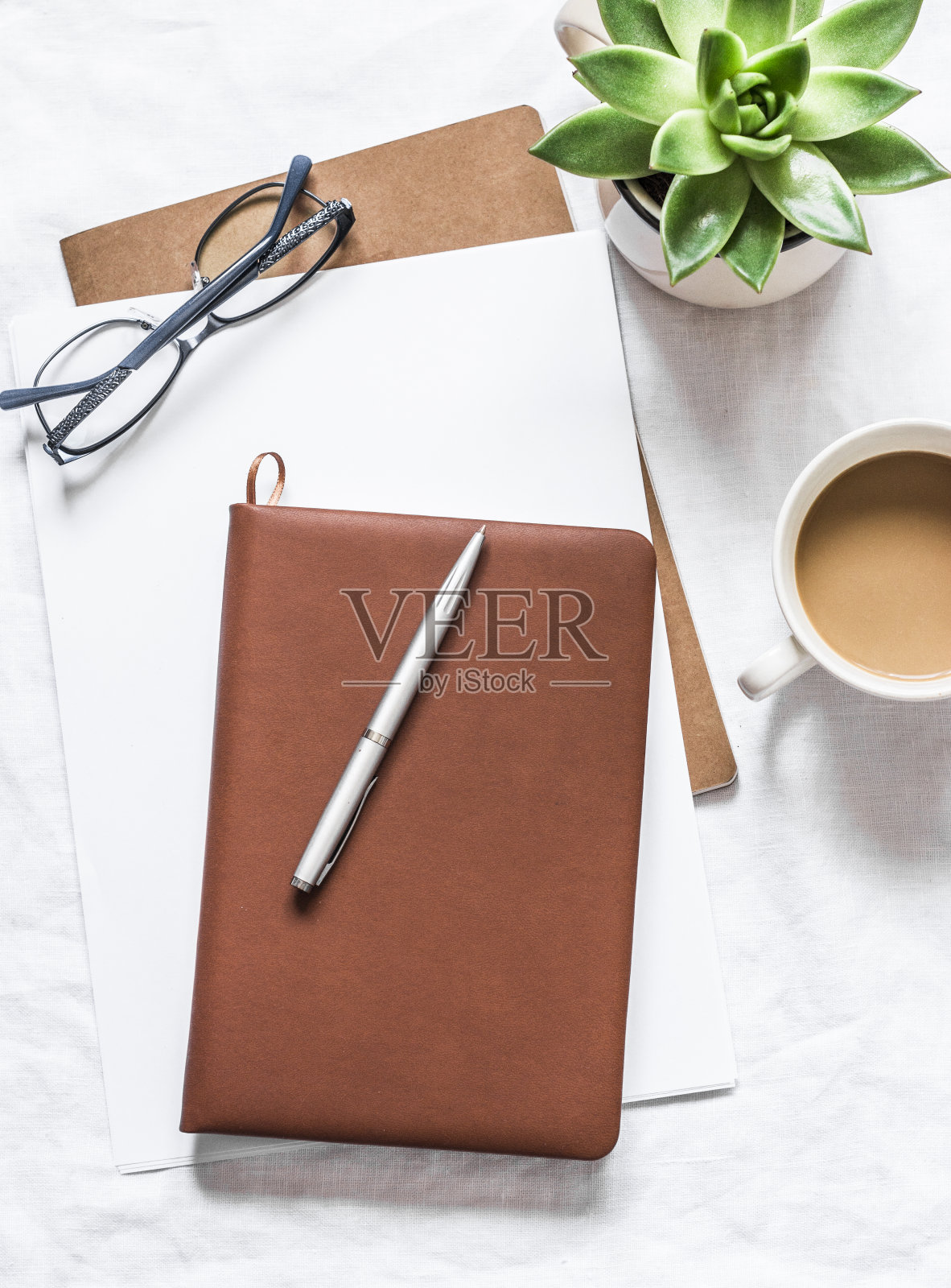 女性办公空间与笔记本，笔，花和一杯咖啡在一个灯光背景，俯视图照片摄影图片