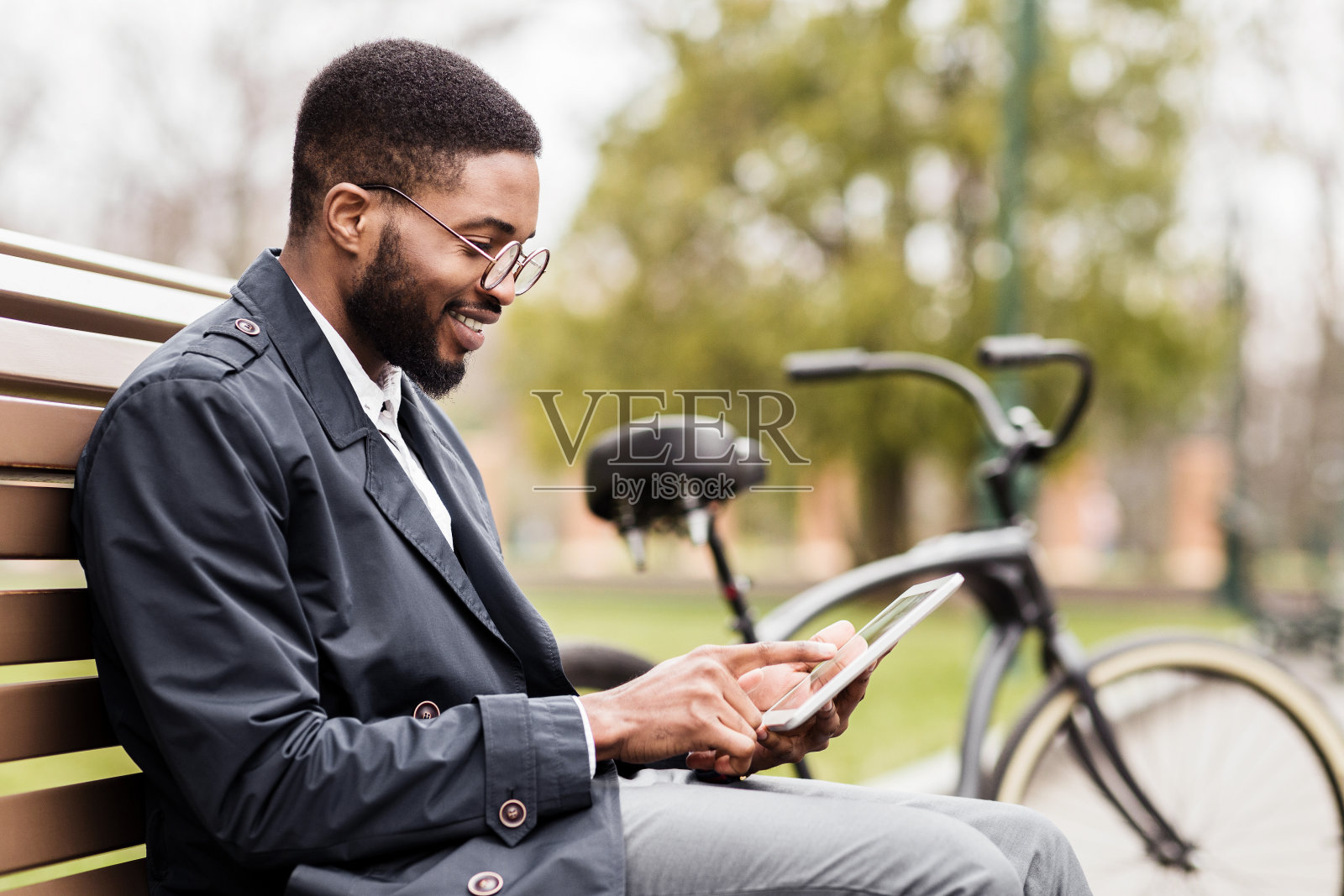 自由的工作。一个年轻人在公园里用平板电脑照片摄影图片