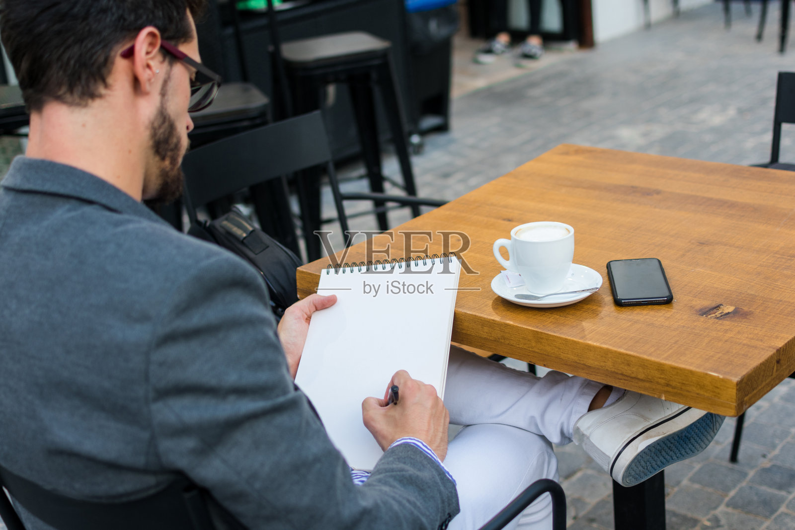 一位年轻的商人正在酒吧的露台上写他的笔记本照片摄影图片