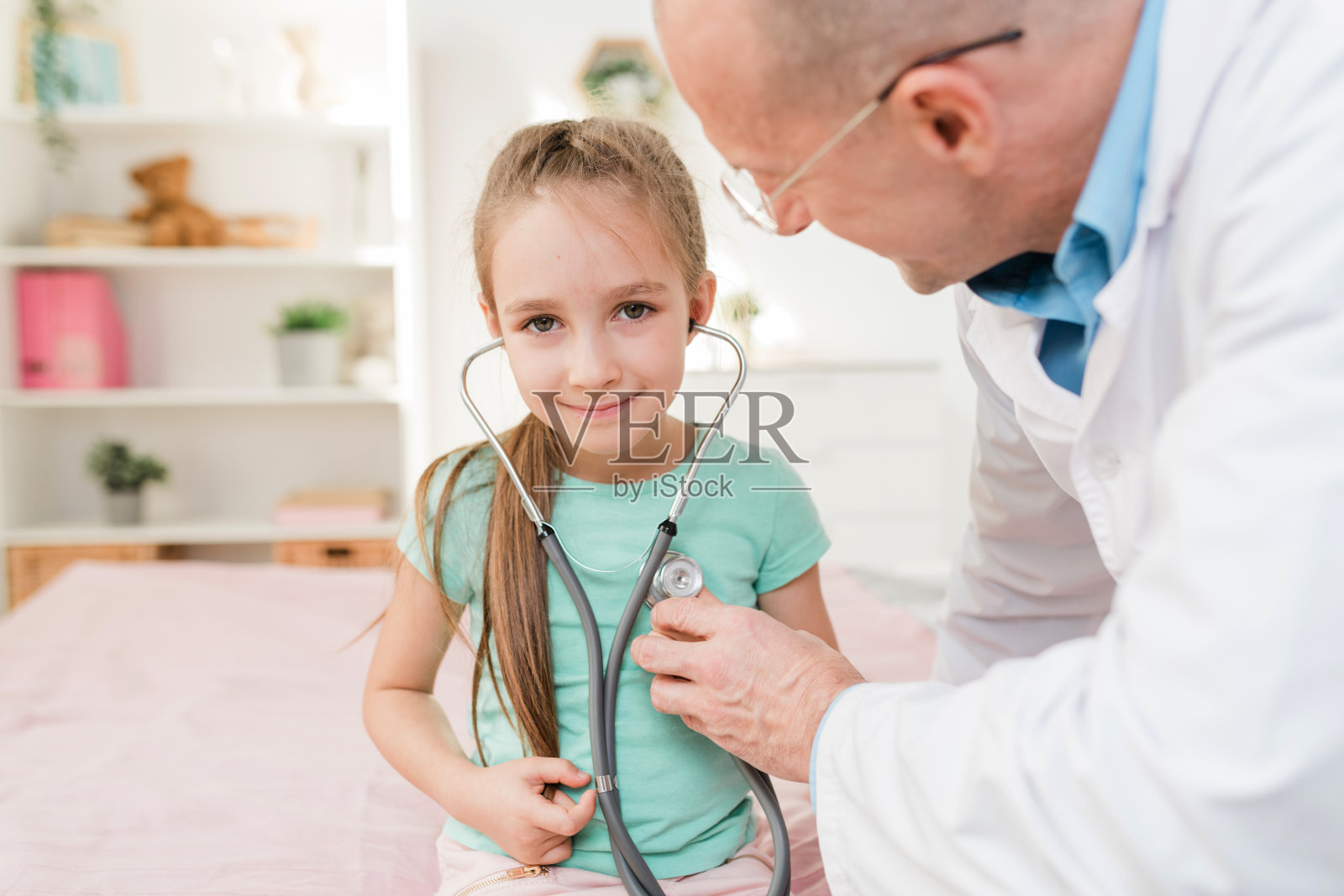 微笑的小女孩与听诊器听她的心跳照片摄影图片