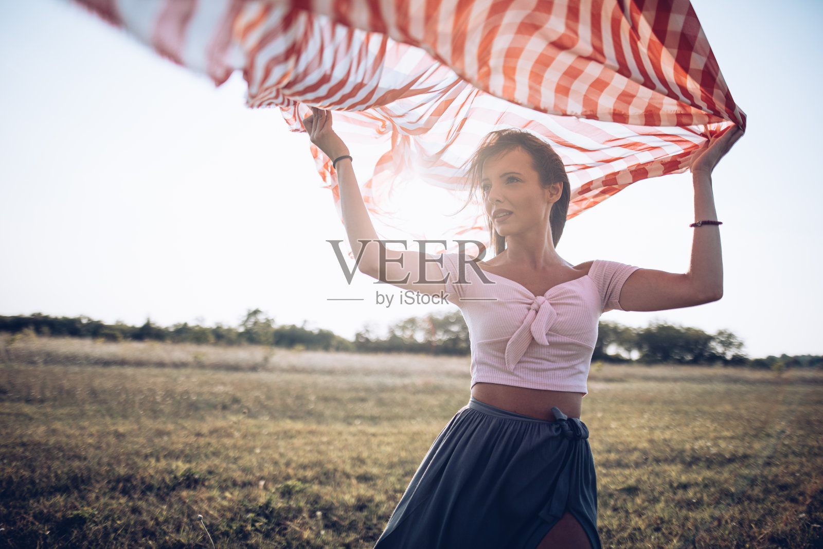 在一个刮风的日子里，一个漂亮的女人摆弄着一条围巾照片摄影图片