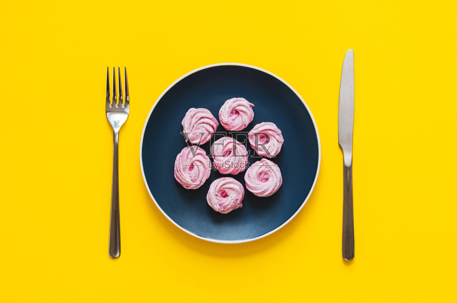 平铺-美味和新鲜的粉红色甜点在彩色盘子上，用叉子和刀在黄色的背景。照片摄影图片