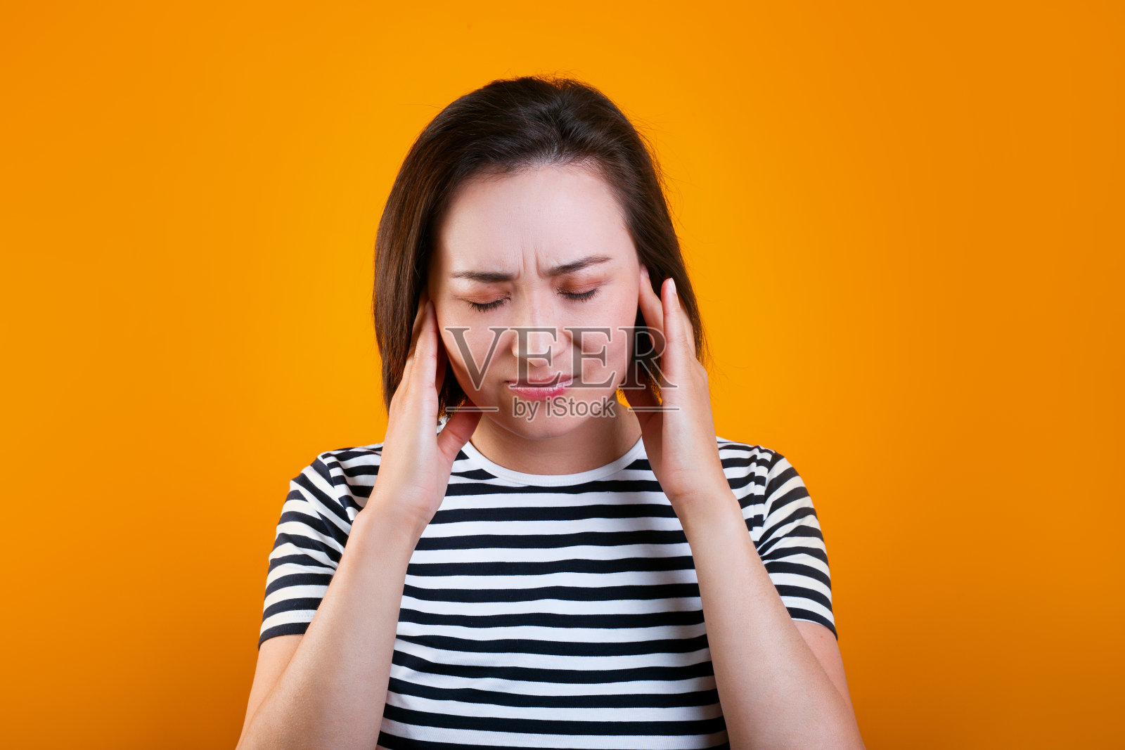 疲惫的混血年轻棕发女子按着太阳穴，在黄色背景上闭着眼睛照片摄影图片