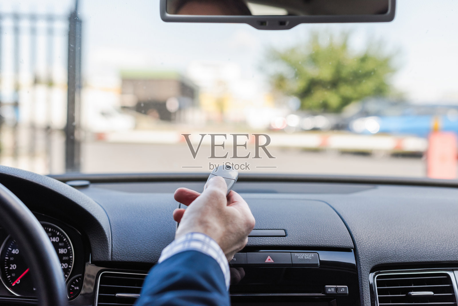 近距离商务手使用遥控打开自动屏障，坐在汽车和离开停车场。照片摄影图片