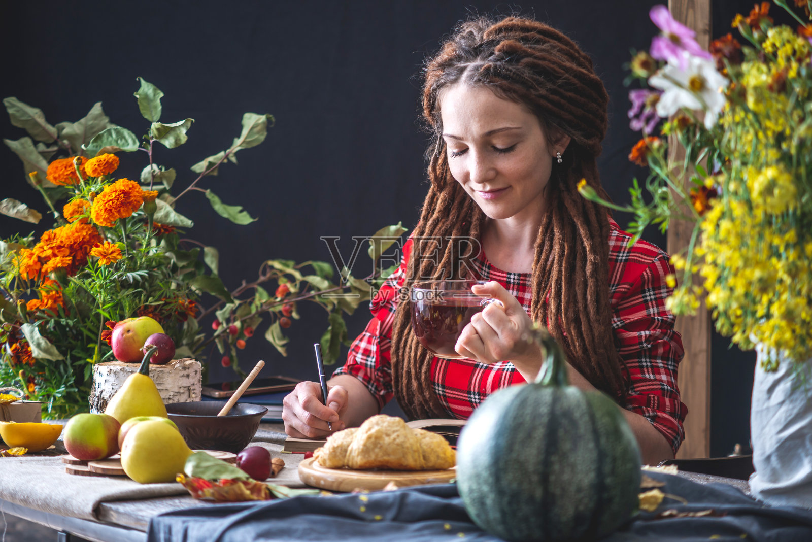 美丽的年轻女子在笔记本上写下了秋天的梦想。秋天的桌子与花。秋意浪漫心情照片摄影图片
