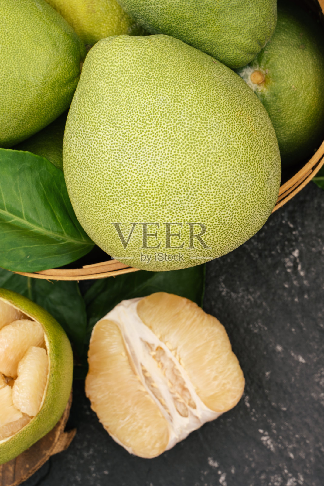 新鲜去皮柚子，柚子，柚子，柚子放在竹篓里，背景色深。秋天季节性的水果照片摄影图片