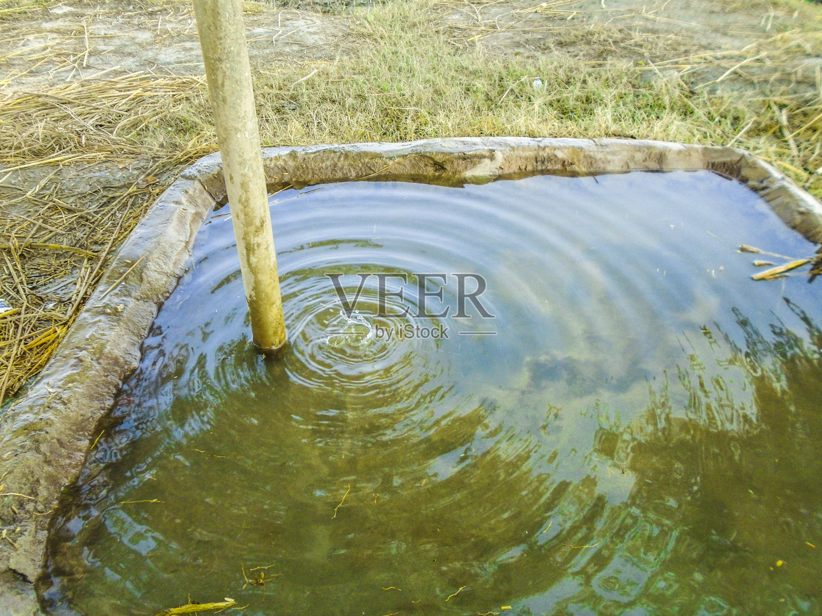 一个生锈的水泵水泵出的水导致气候变化和干燥的土地在背景照片摄影图片