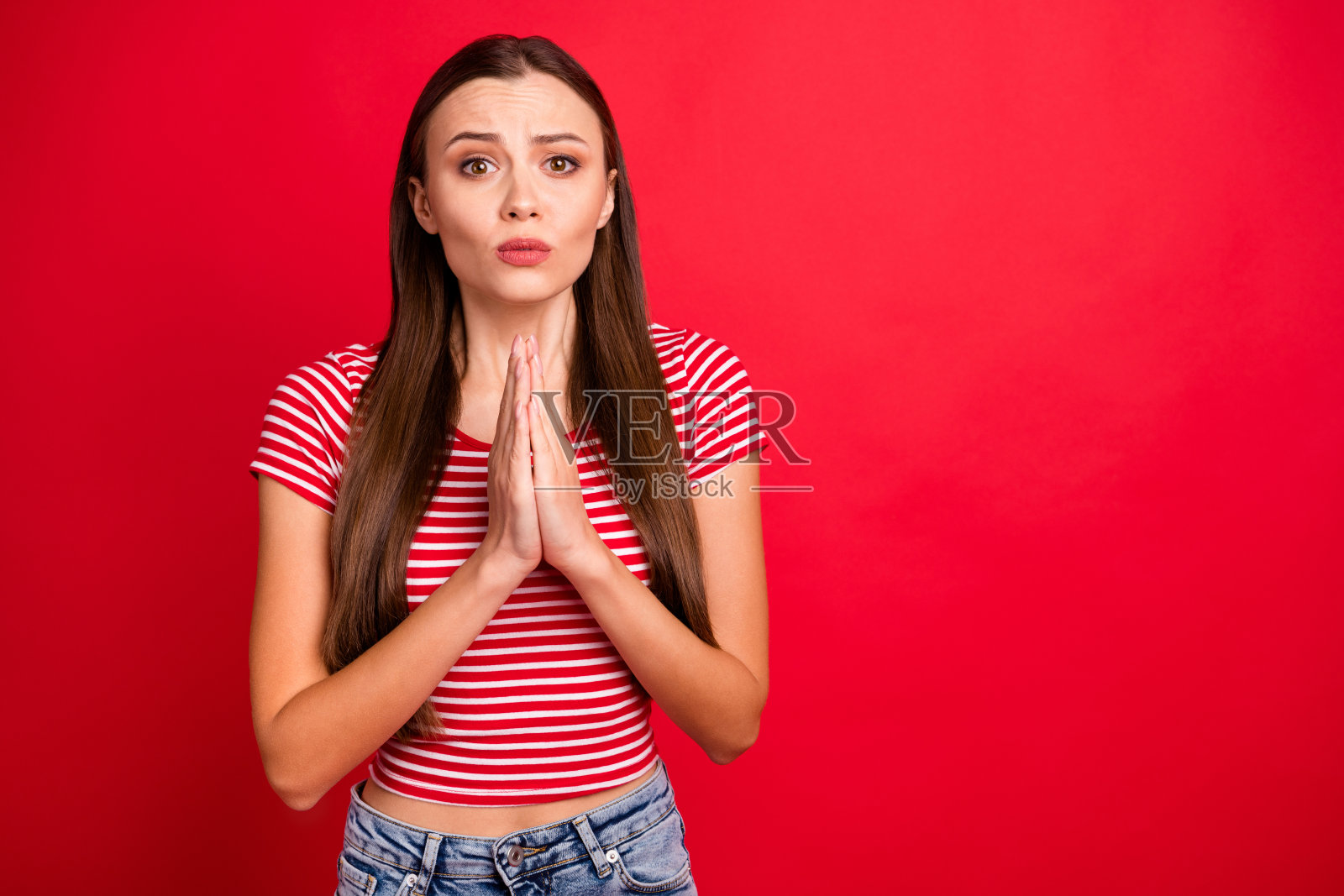照片心烦可爱漂亮迷人的女孩乞求某人买她想要的东西穿着条纹t恤，而孤立的红色背景照片摄影图片