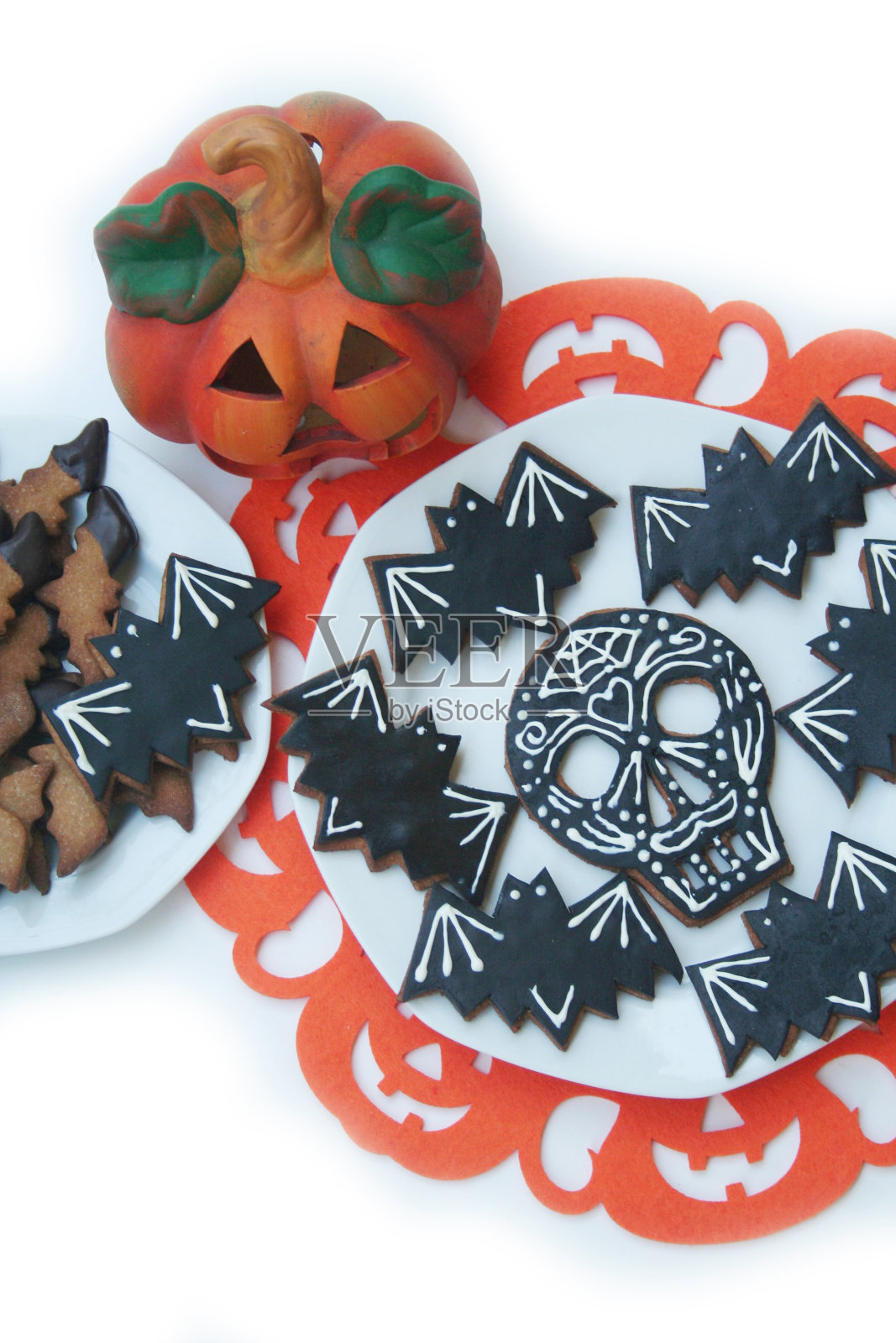 万圣节饼干的形状是一个头骨和蝙蝠在盘子上白色照片摄影图片