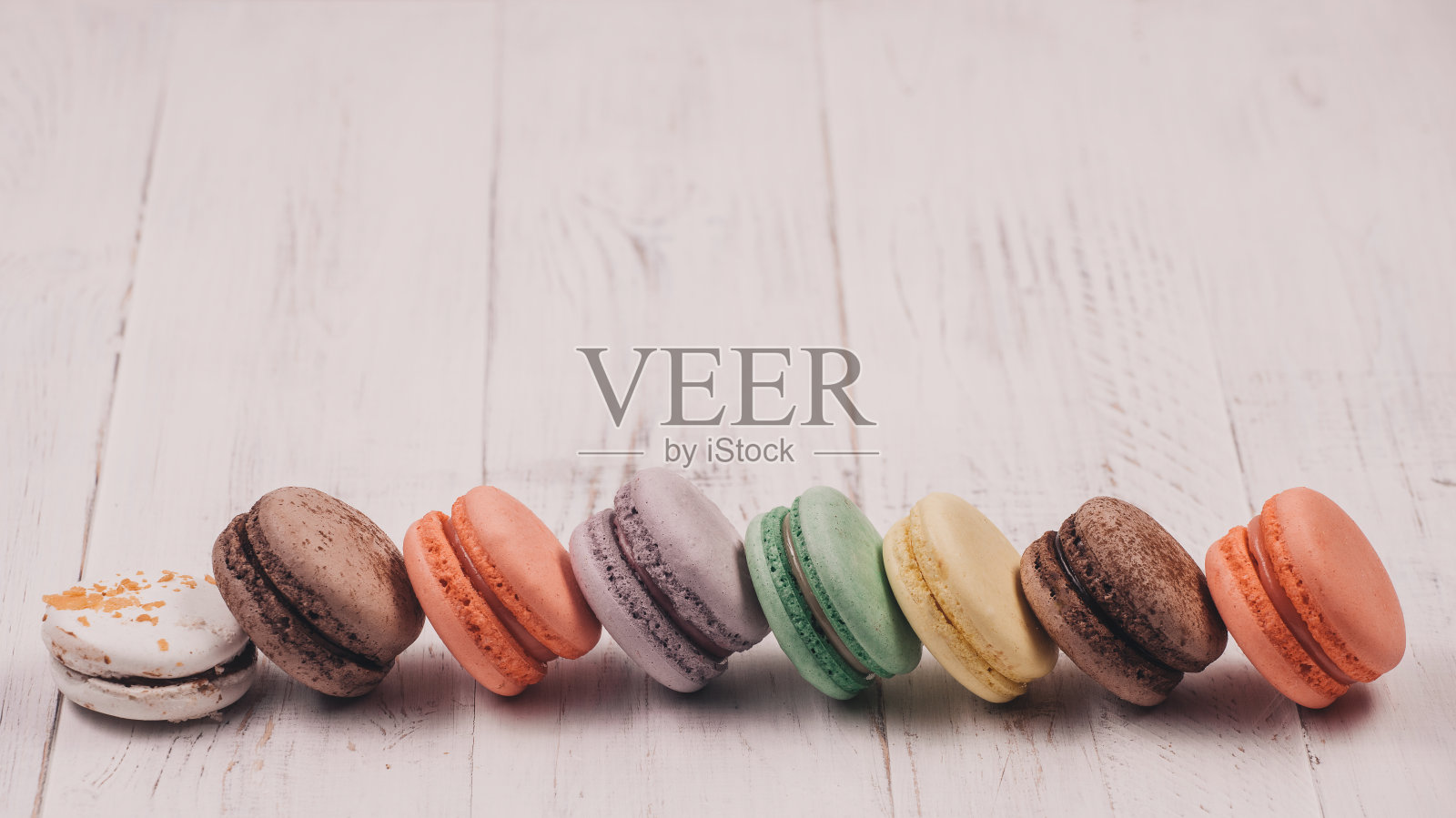 靠近彩色的马卡龙在白色的桌子背景。传统的法国甜点。甜蜜的美味的食物照片摄影图片