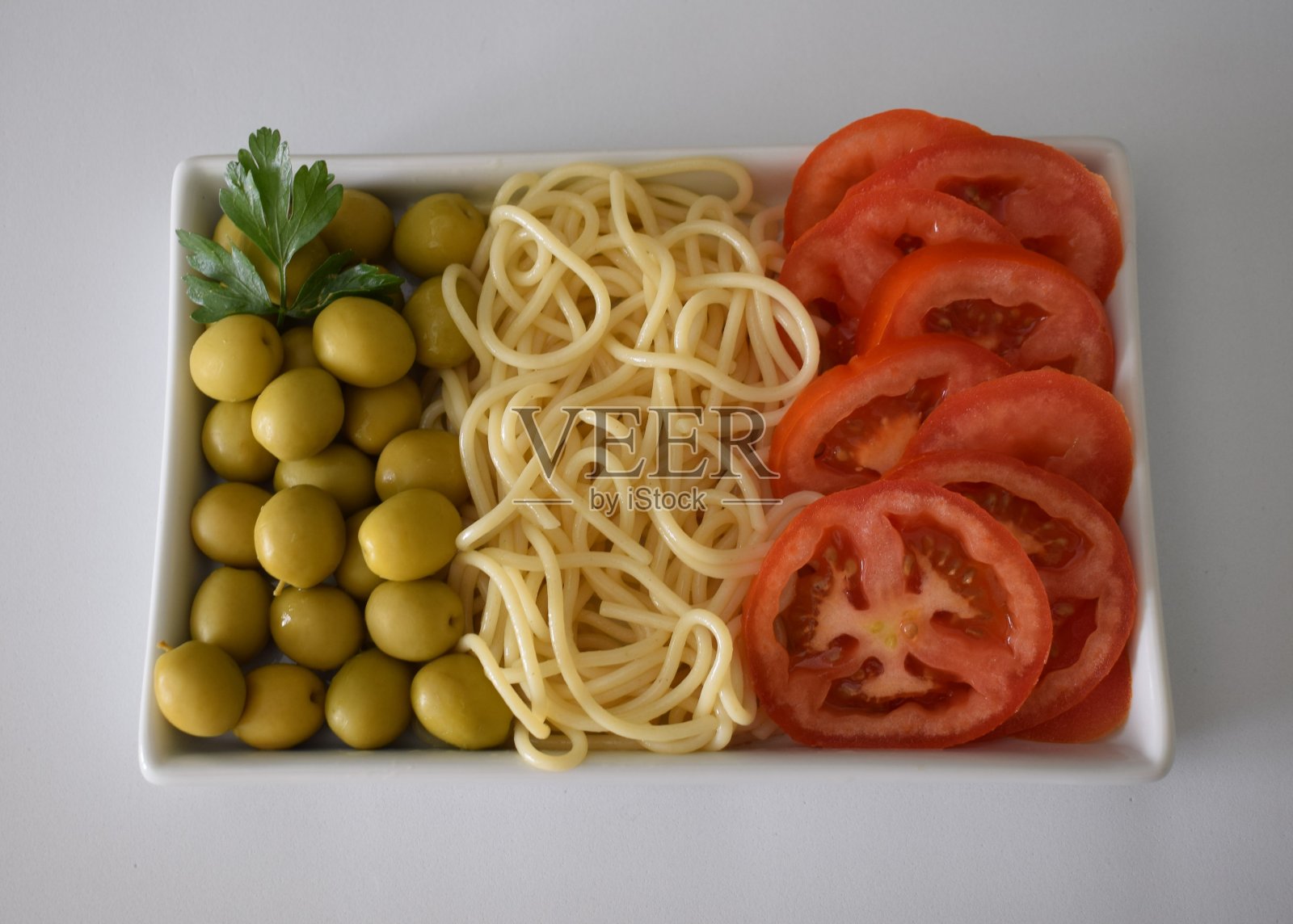 用食物、白色盘子和白色背景做成的意大利国旗。照片摄影图片