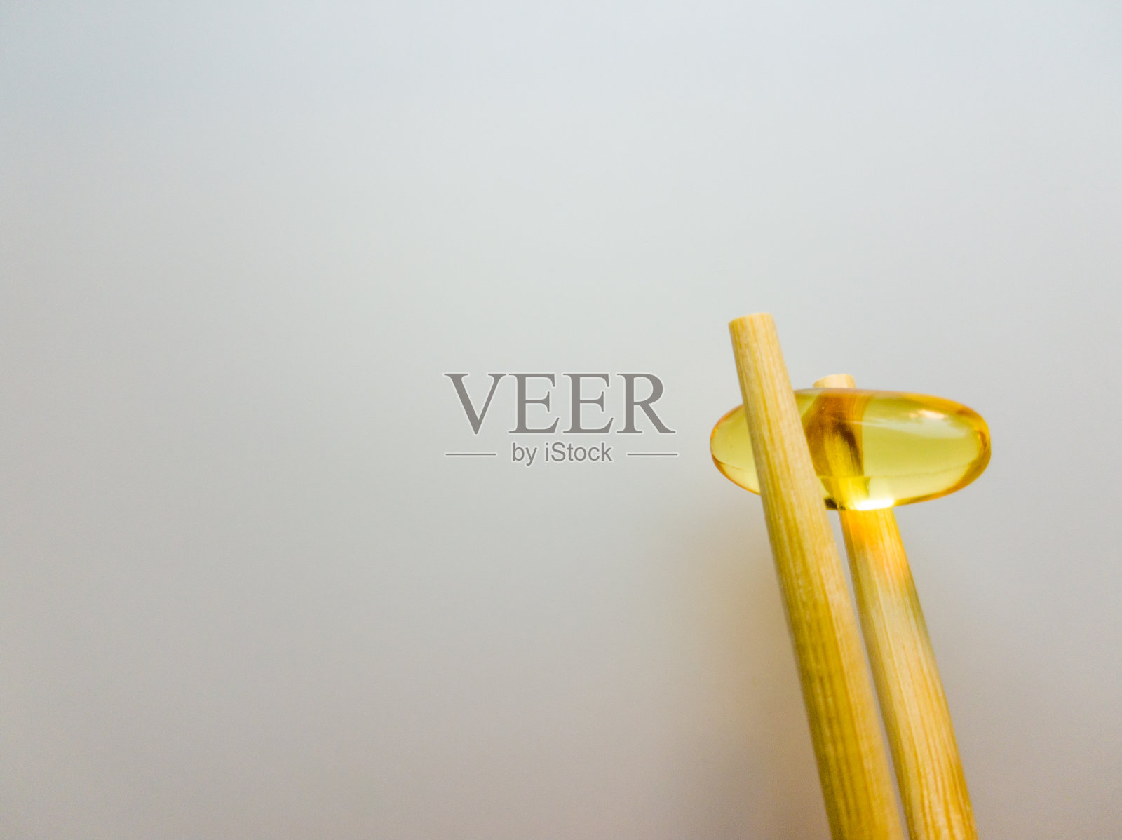 用筷子夹鱼油胶囊。鱼油胶囊。白色背景上的欧米茄3鱼油胶囊。高分辨率的产品。食物补充。-6， -9，维生素A, D, D3, E照片摄影图片