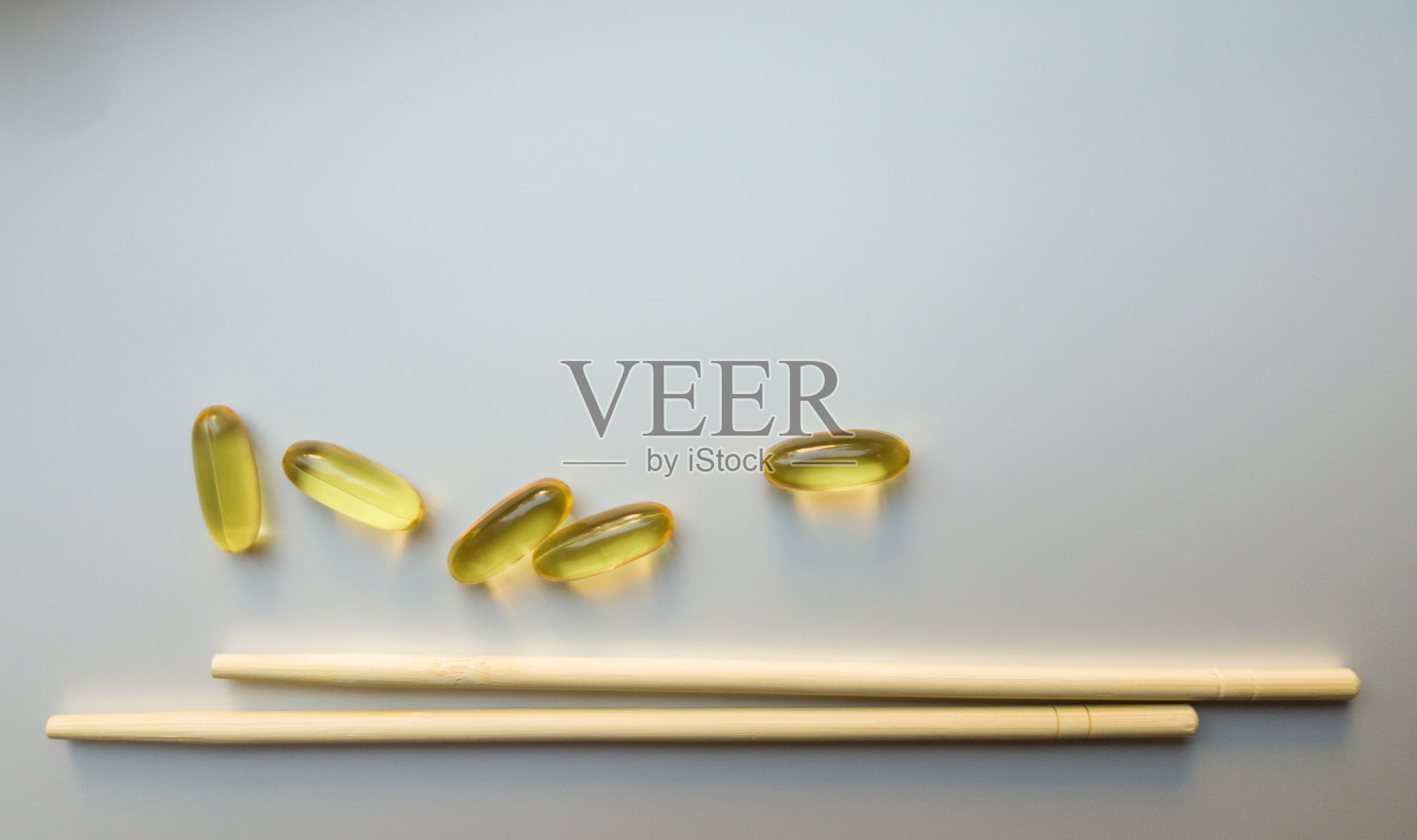 用筷子夹鱼油胶囊。鱼油胶囊。白色背景上的欧米茄3鱼油胶囊。高分辨率的产品。食物补充。-6， -9，维生素A, D, D3, E照片摄影图片