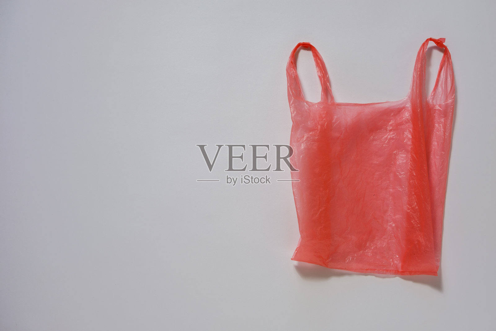 灰色上的皱巴巴的红色塑料袋照片摄影图片