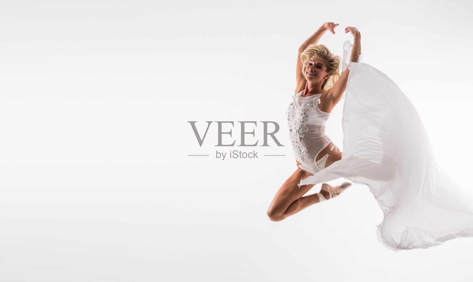 优雅的芭蕾舞者在白色连衣裙在工作室跳跃照片摄影图片