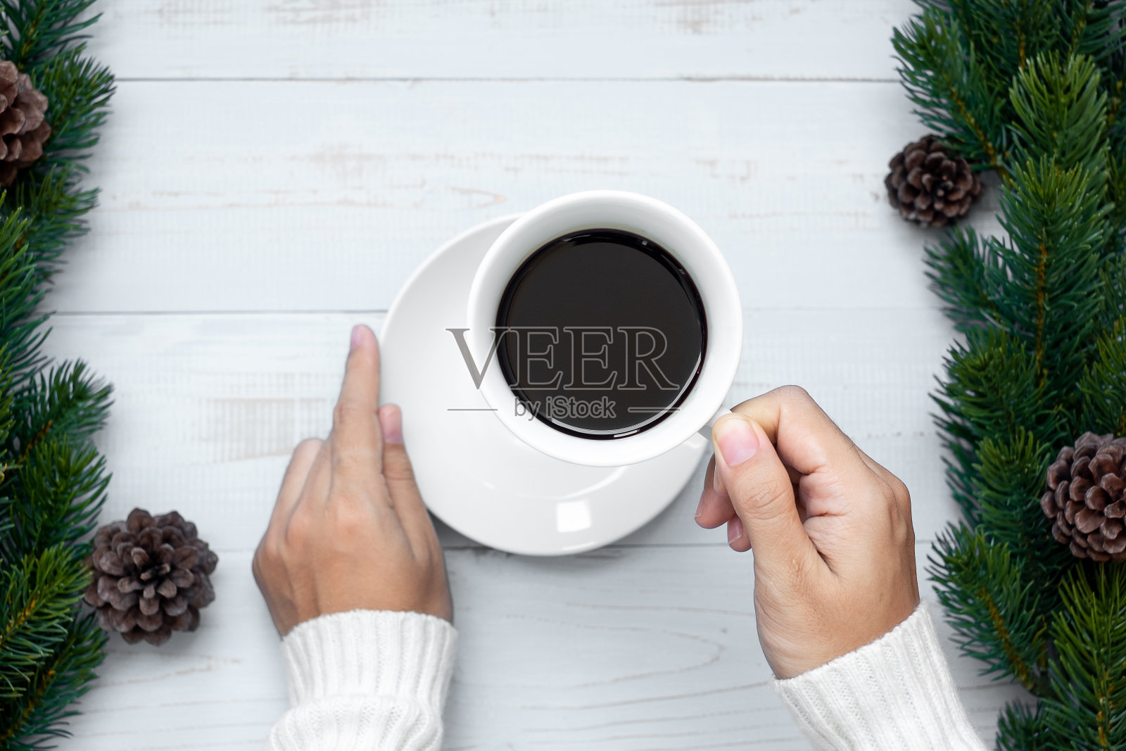 女人手拿着黑色的咖啡杯与圣诞装饰，新年和圣诞假期快乐照片摄影图片