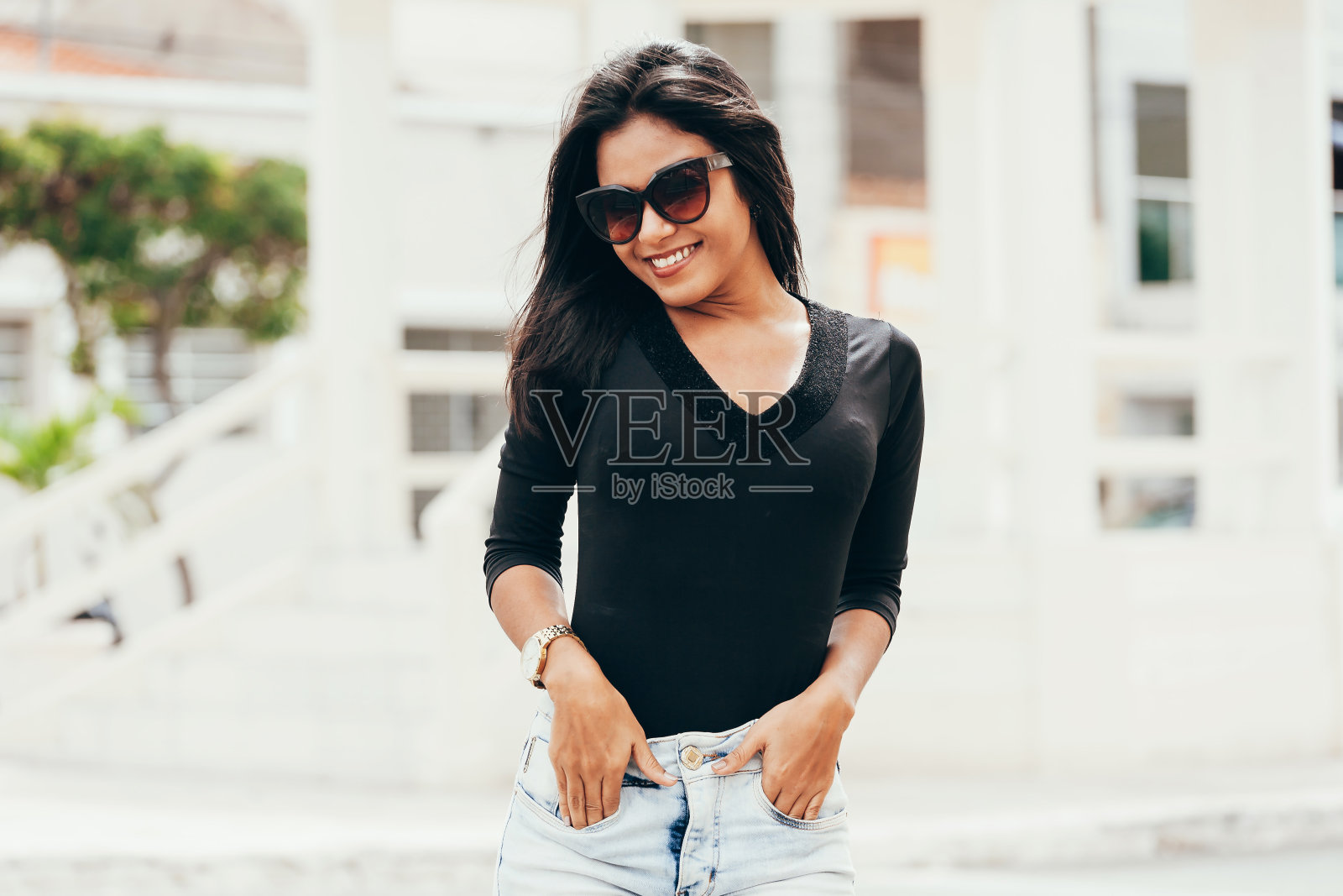 一个年轻漂亮的女人戴着墨镜在城市里的肖像照片摄影图片