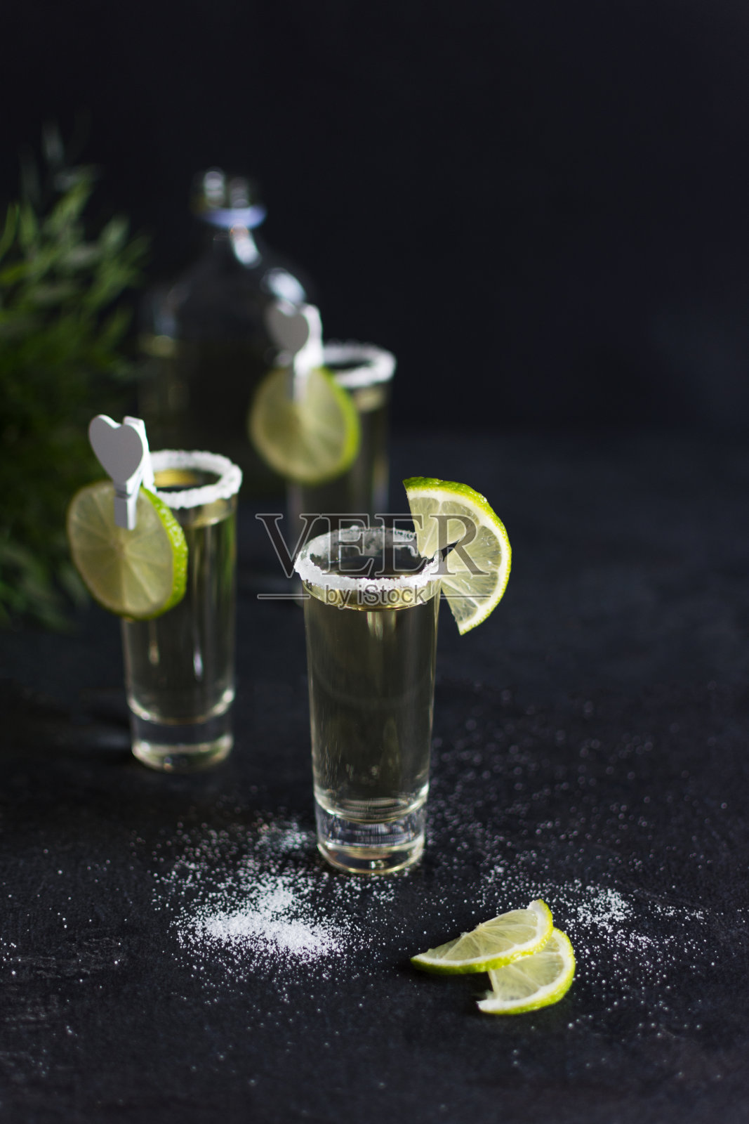 金色龙舌兰杯中点缀着盐和酸橙片。照片摄影图片