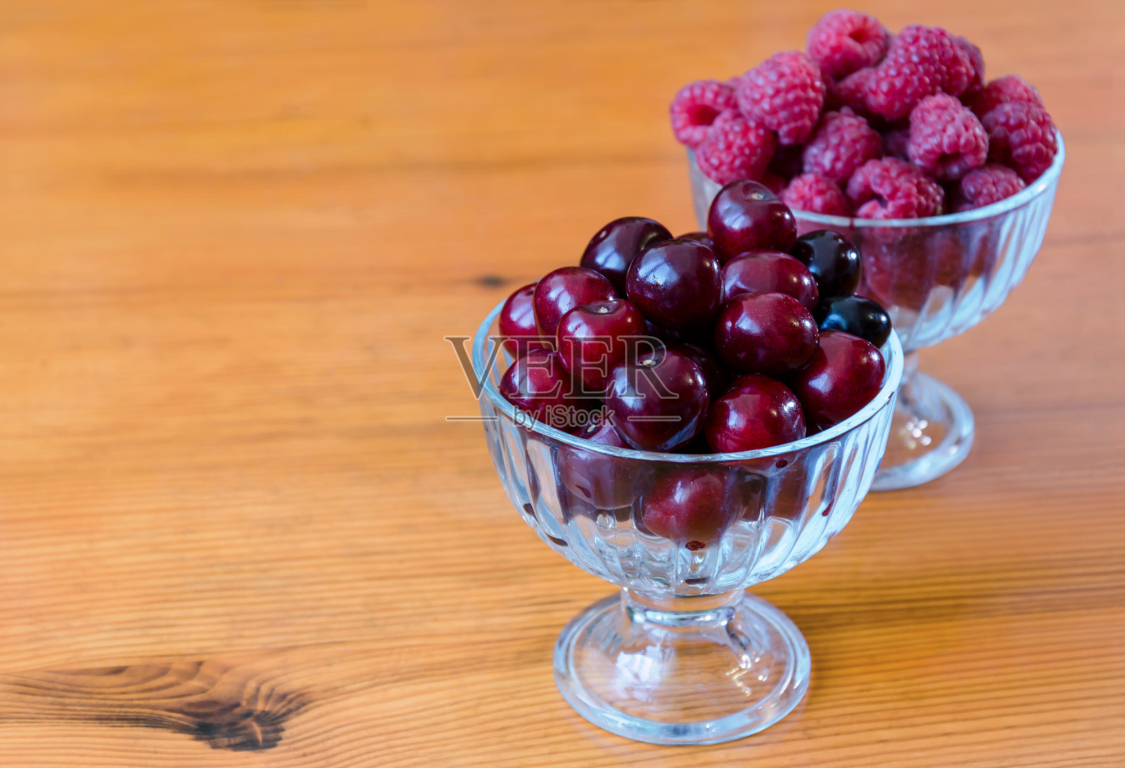大量的红覆盆子和樱桃放在玻璃碗里照片摄影图片