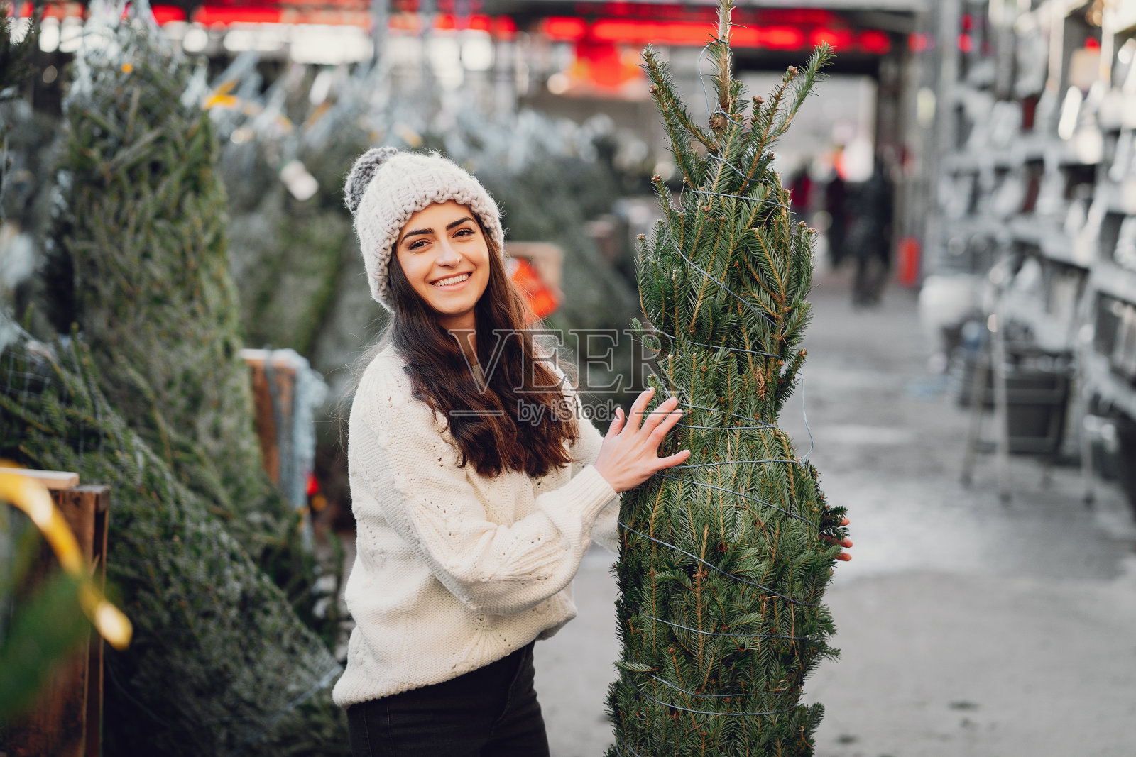 可爱的棕发女孩，穿着白色毛衣和圣诞树照片摄影图片
