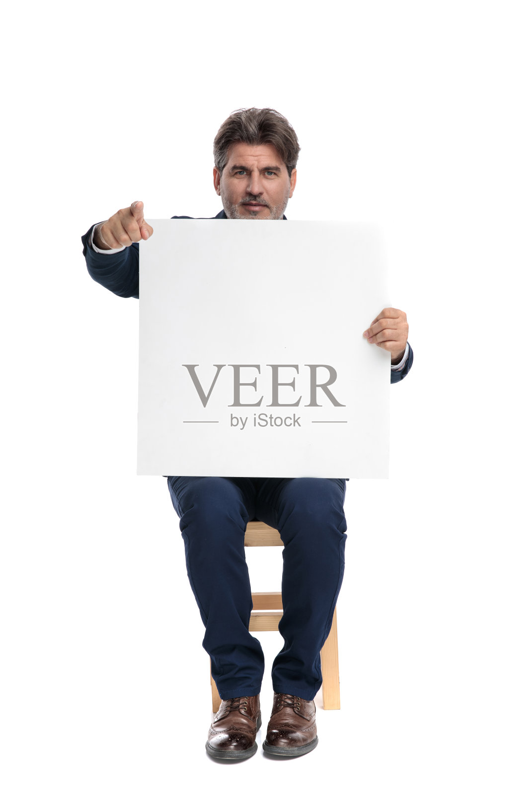 商人坐在广告牌前，指着前方照片摄影图片