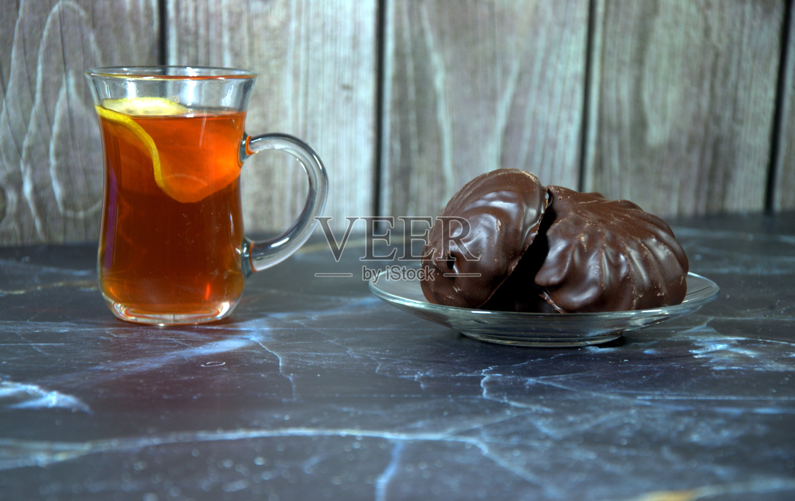 一杯茶，一片柠檬和一个盘子，两个巧克力棉花糖。照片摄影图片