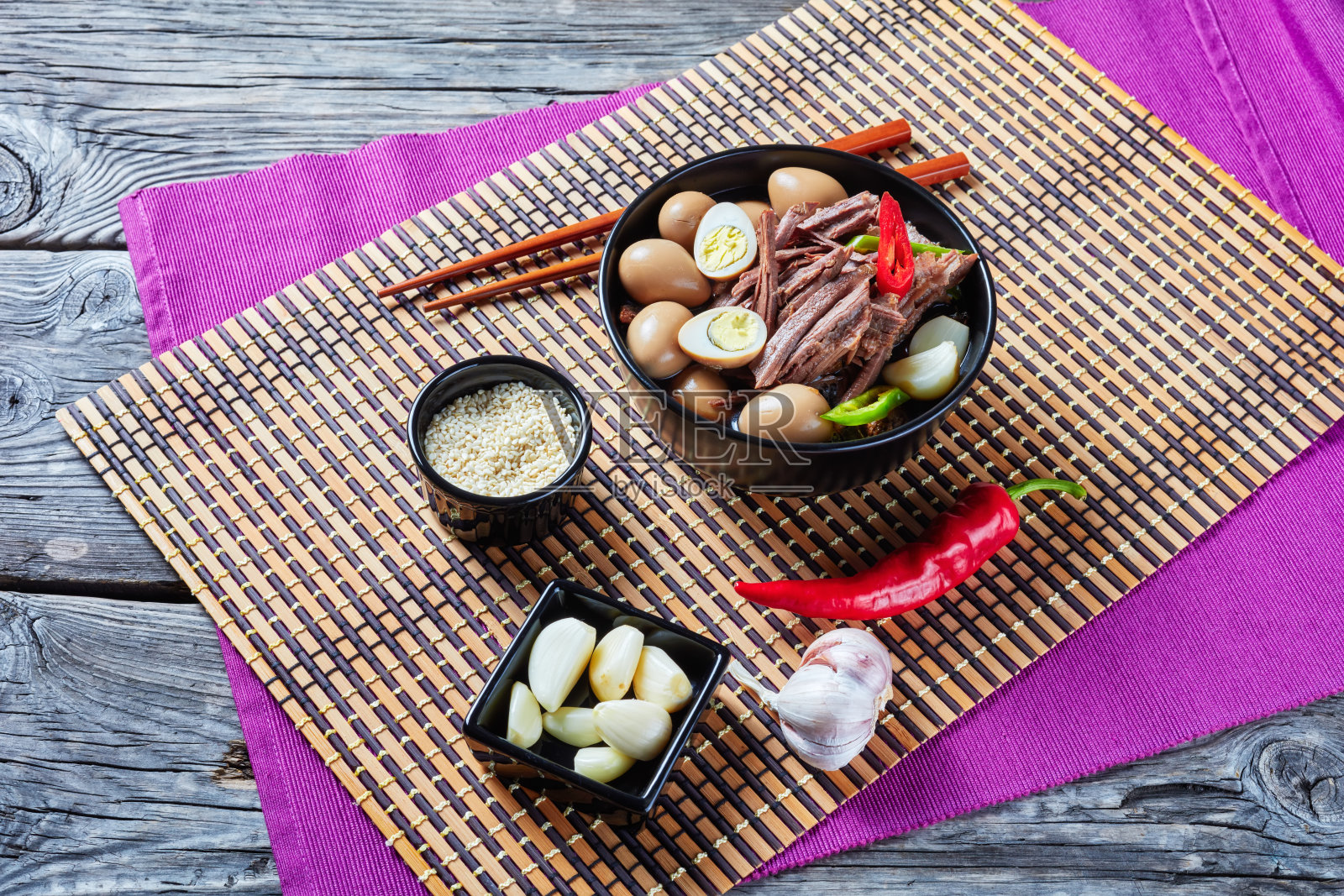 用酱油炖牛肉，配鹌鹑蛋、蒜瓣和红辣椒片照片摄影图片