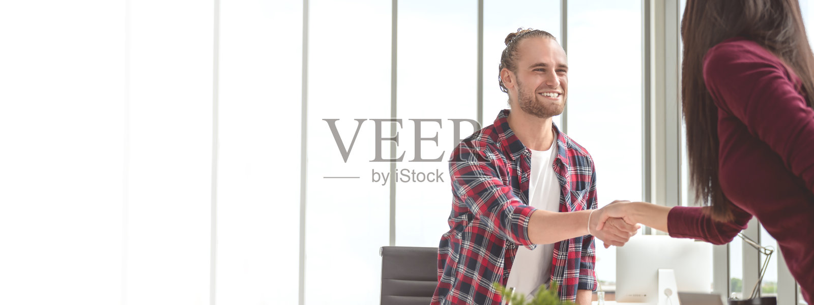 自信的年轻白种人男人握手与合作伙伴女人在商业协议微笑一起感到幸福。旗帜的年轻商业夫妇在交易，合作和握手的概念。照片摄影图片