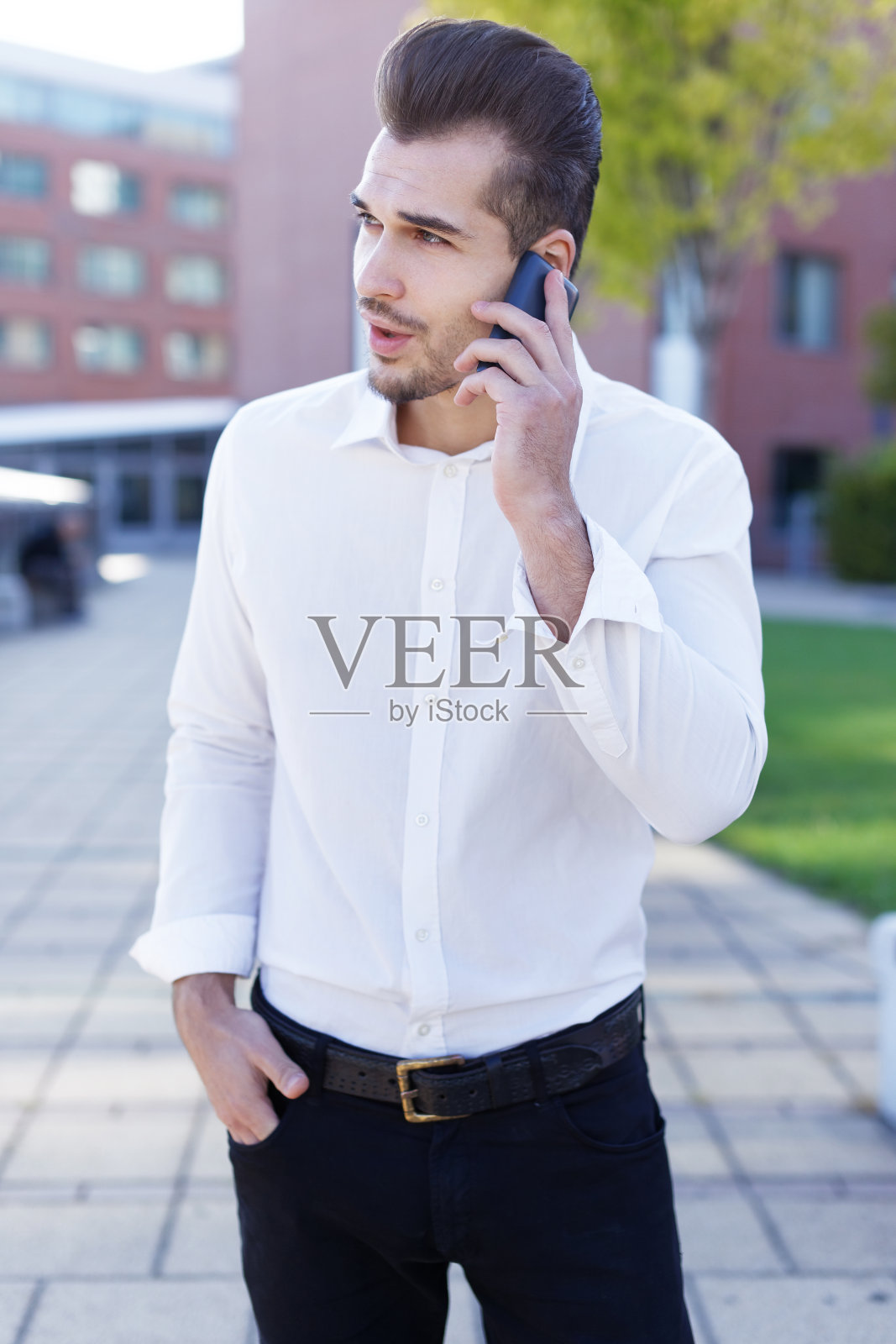 年轻的商人打电话到公园看向别处照片摄影图片