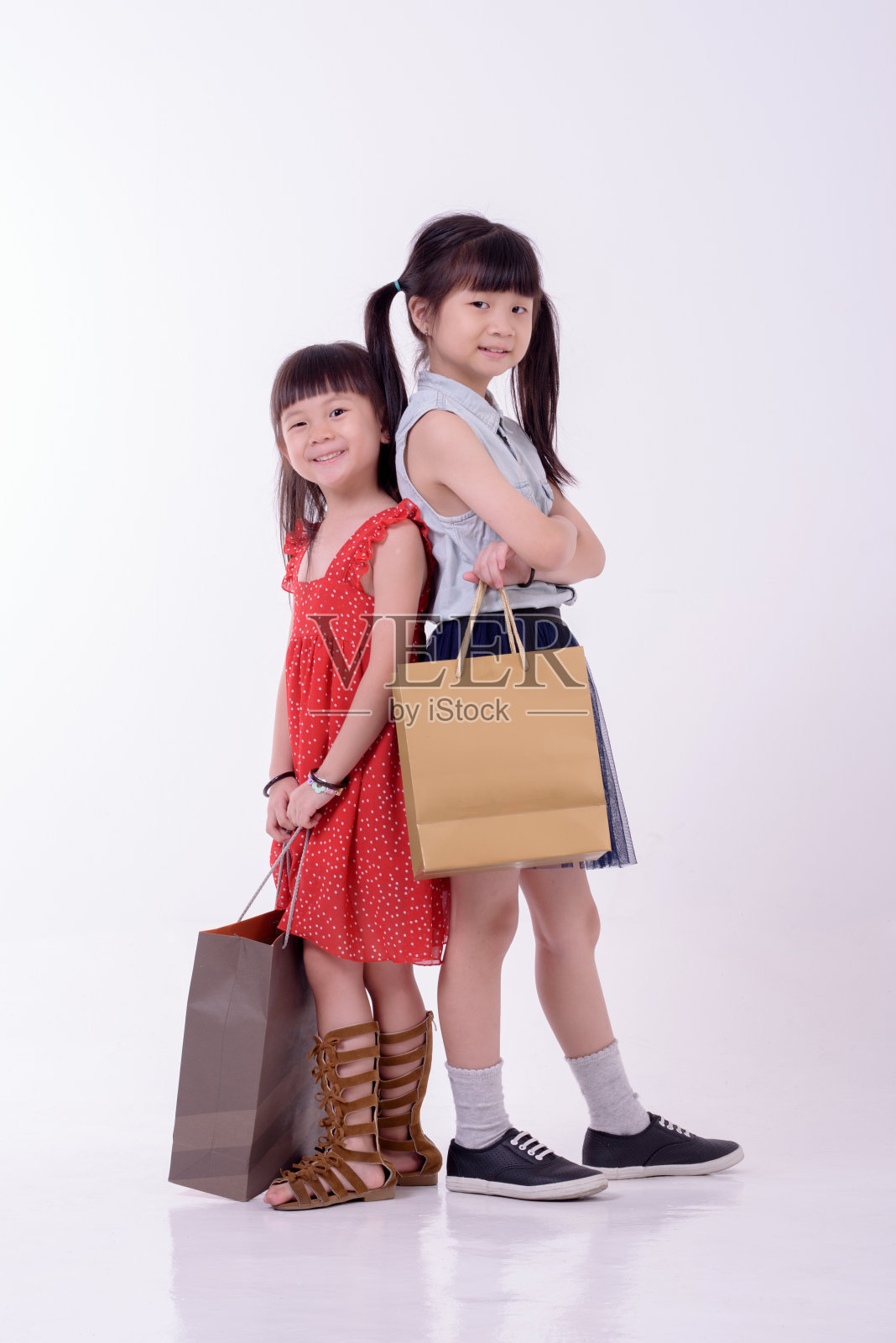 两个迷人的小亚洲可爱的女孩拿着购物纸袋照片摄影图片