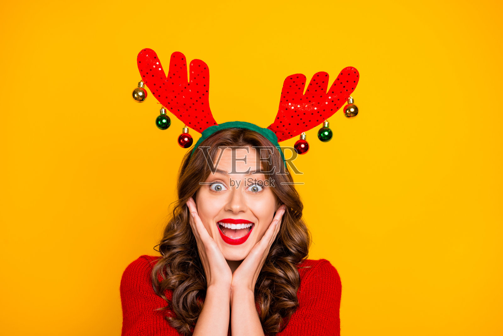 漂亮的女士喜出望外的圣诞节装饰头角和针织套衫孤立黄色背景照片摄影图片