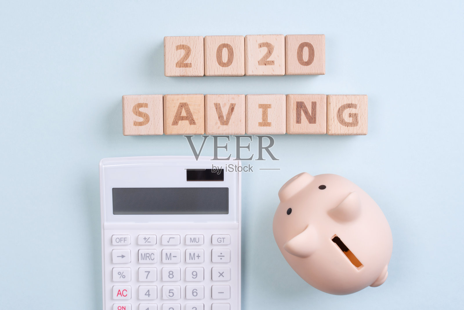 摘要2020年金融目标设计理念——几何木块立方体上的蓝色桌子背景与储蓄罐。照片摄影图片