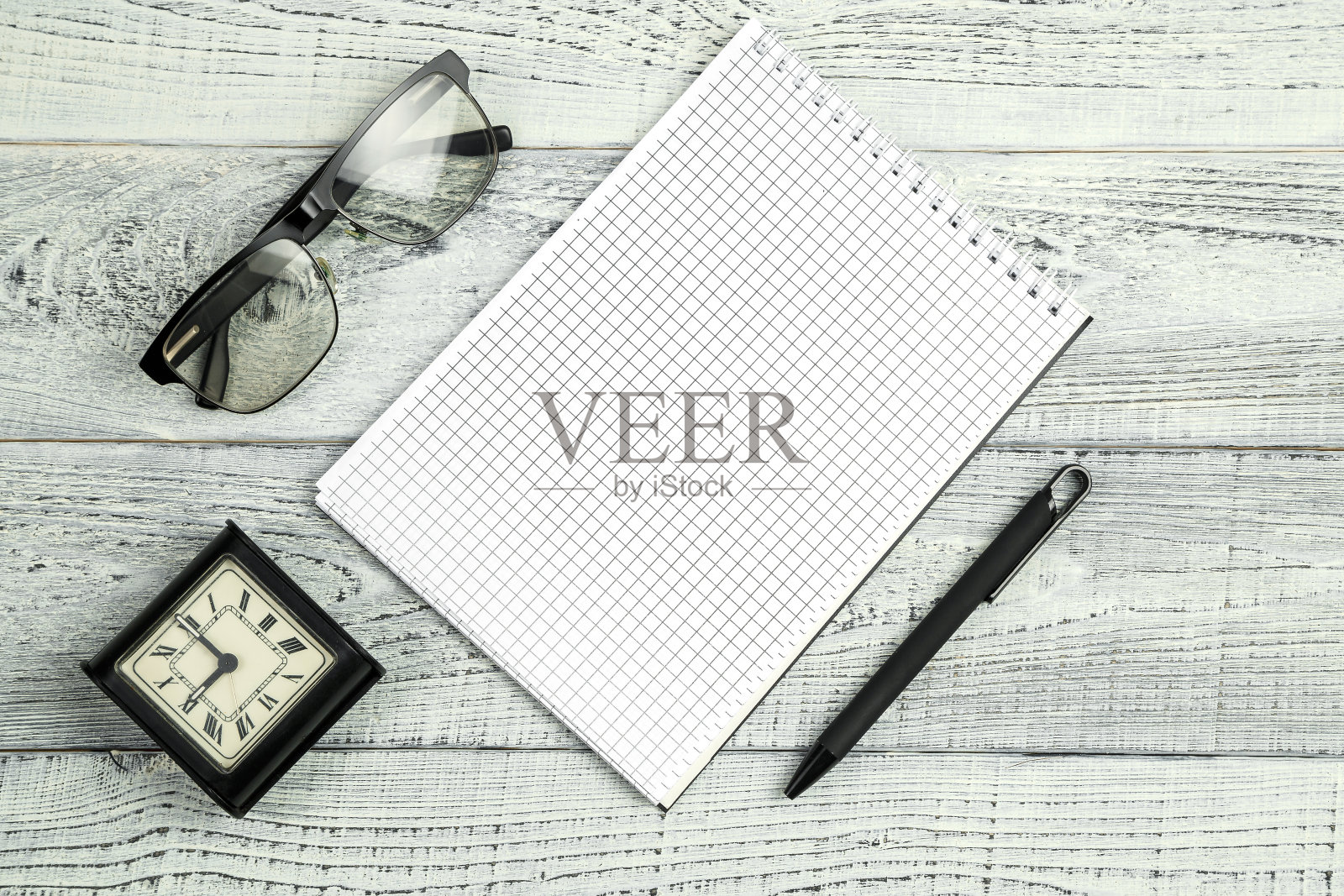 早....复古闹钟，纸笔记本，笔和太阳镜，眼镜在破旧的白色木制背景照片摄影图片