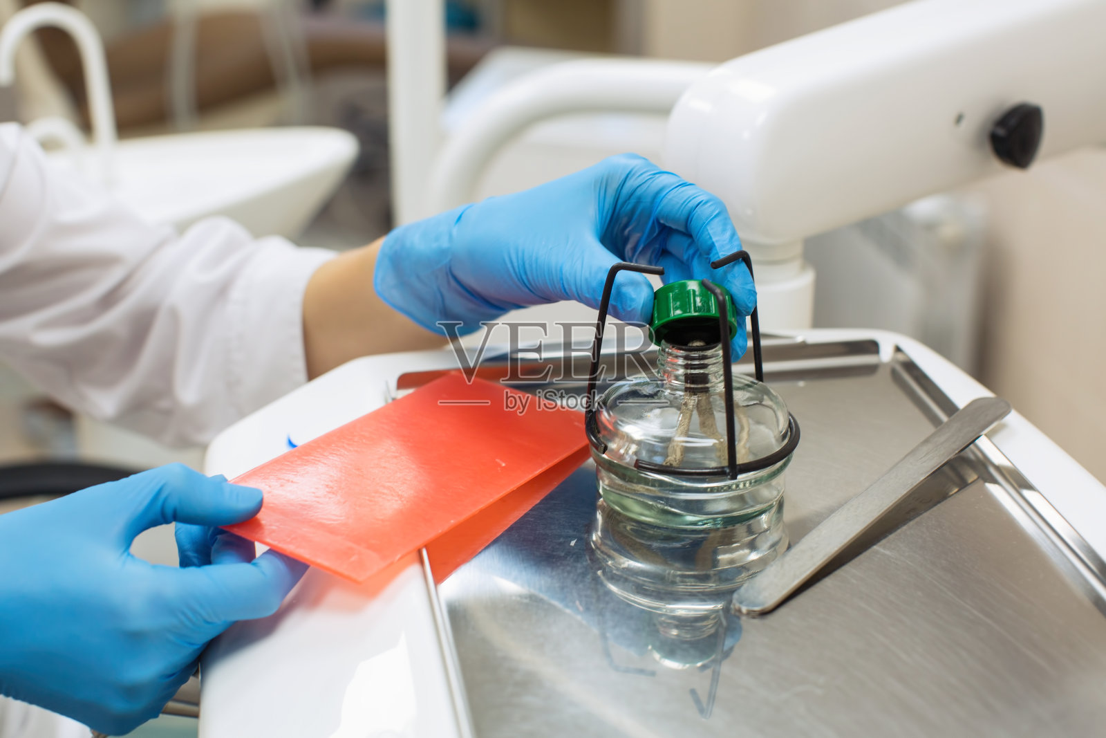 在牙科诊所手持酒精灯或酒精灯及蜡的女牙医。实验室设备、医学与科学、口腔保健理念。照片摄影图片